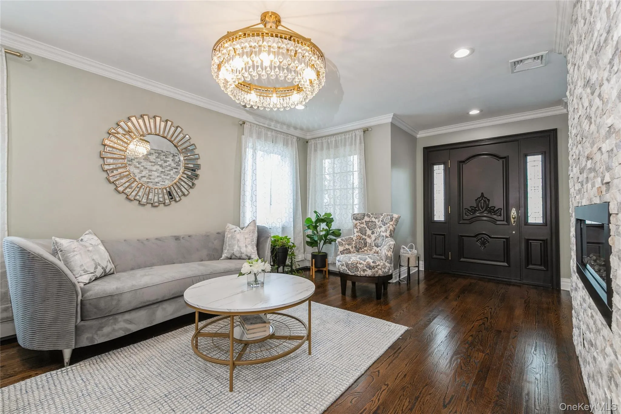 Living area with wood finished floors, a chandelier, and crown molding Living area with wood finished floors, a chandelier, and crown molding