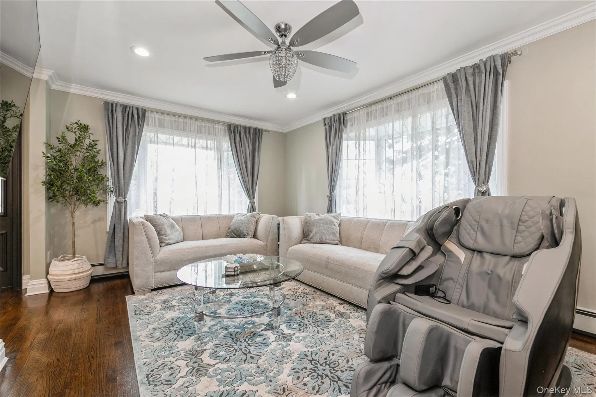 Living room with a ceiling fan, wood finished floors, crown molding, recessed lighting, and a baseboard heating unit Living room with a ceiling fan, wood finished floors, crown molding, recessed lighting, and a baseboard heating unit