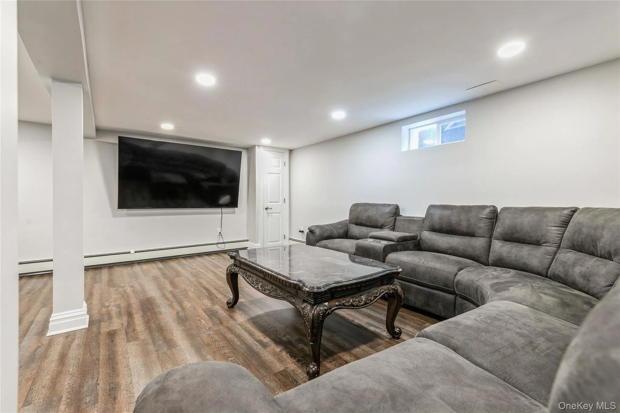 Living area featuring wood finished floors, recessed lighting, and a baseboard radiator Living area featuring wood finished floors, recessed lighting, and a baseboard radiator