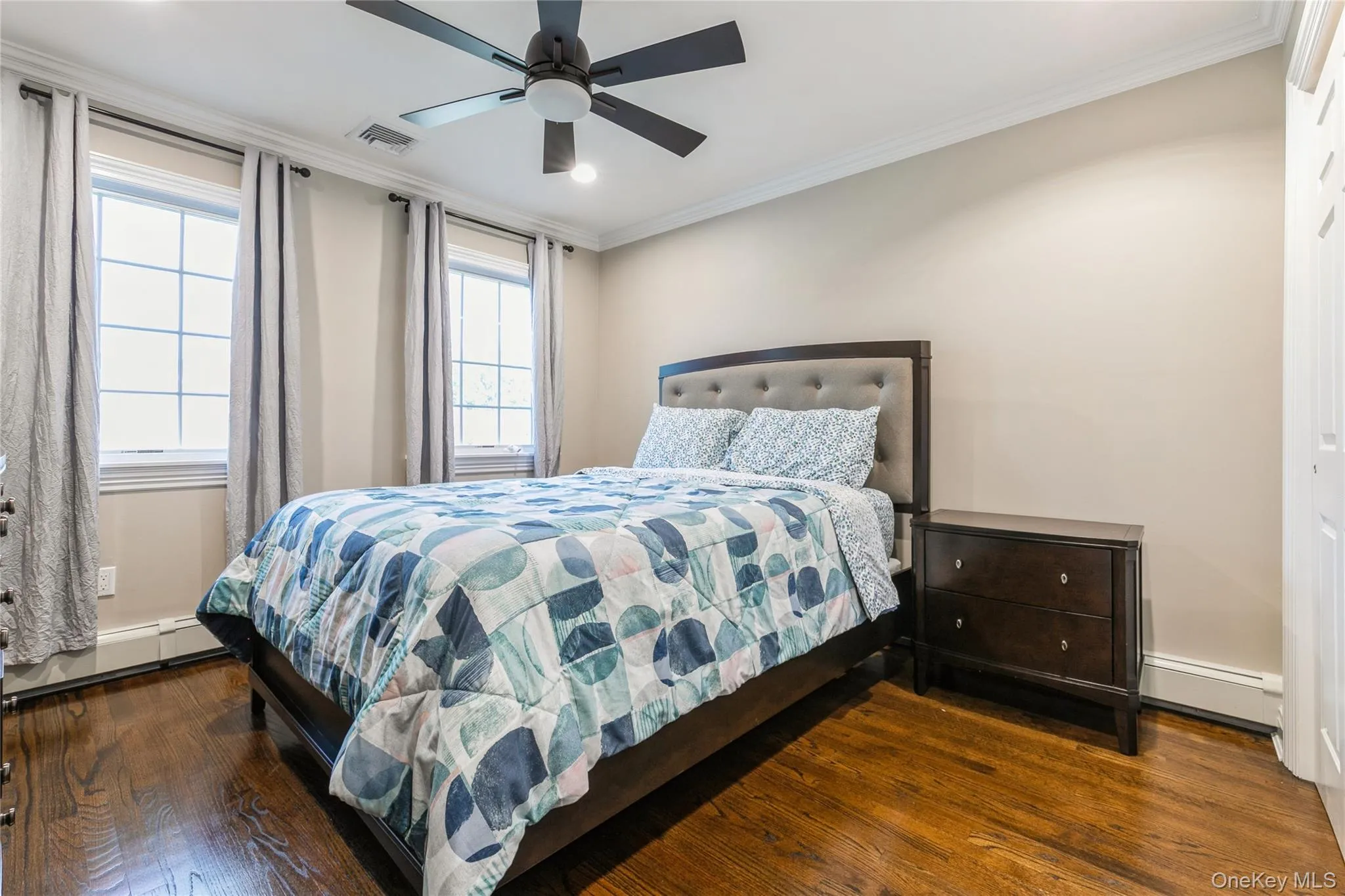 Bedroom with wood finished floors, baseboard heating, ornamental molding, and a ceiling fan Bedroom with wood finished floors, baseboard heating, ornamental molding, and a ceiling fan