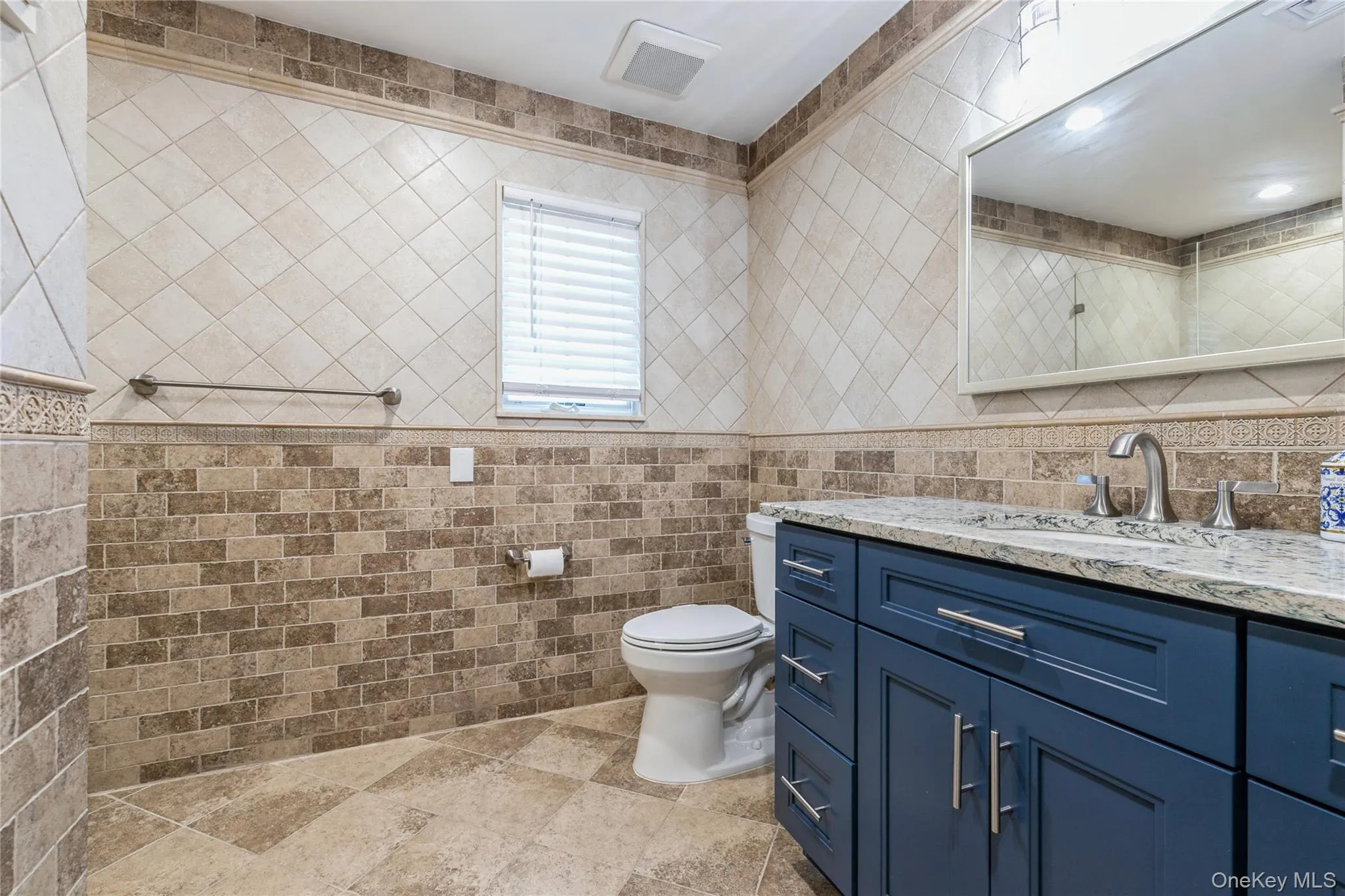 Bathroom with tile walls, vanity, and stone finish floors Bathroom with tile walls, vanity, and stone finish floors
