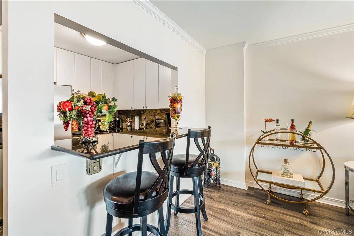 Indoor wet bar with ornamental molding, wood finished floors, and freestanding refrigerator Indoor wet bar with ornamental molding, wood finished floors, and freestanding refrigerator