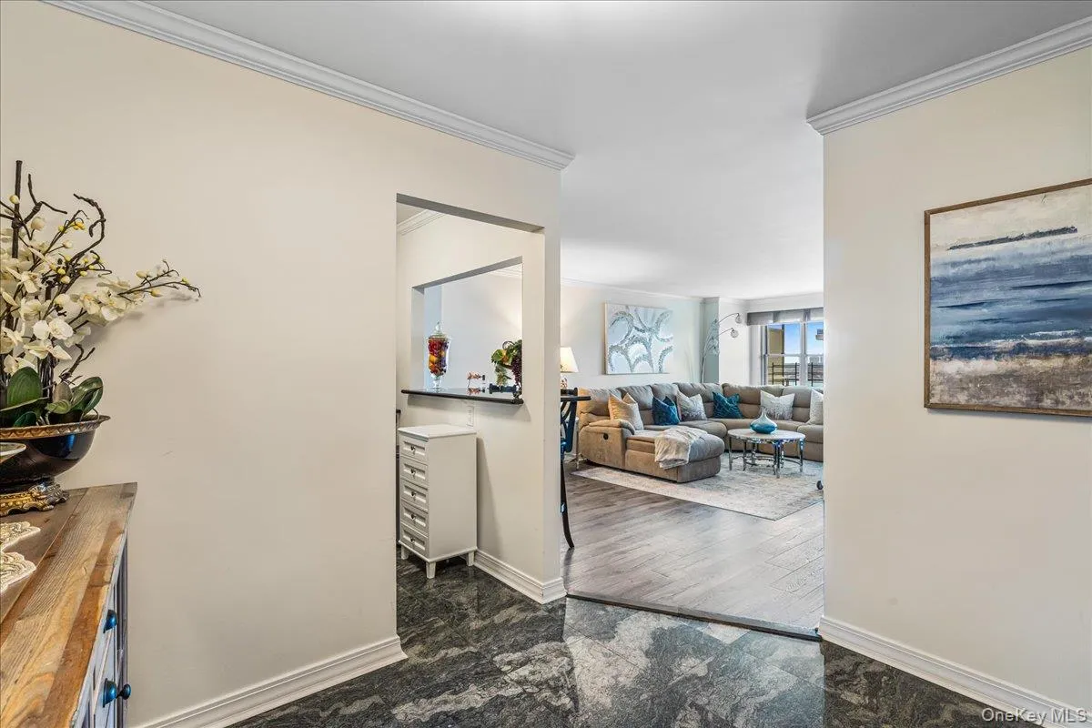 Corridor featuring ornamental molding and dark marble finish flooring Corridor featuring ornamental molding and dark marble finish flooring
