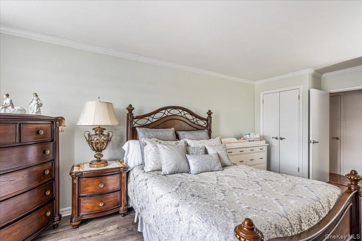 Bedroom featuring ornamental molding, light wood-style floors, and a closet Bedroom featuring ornamental molding, light wood-style floors, and a closet