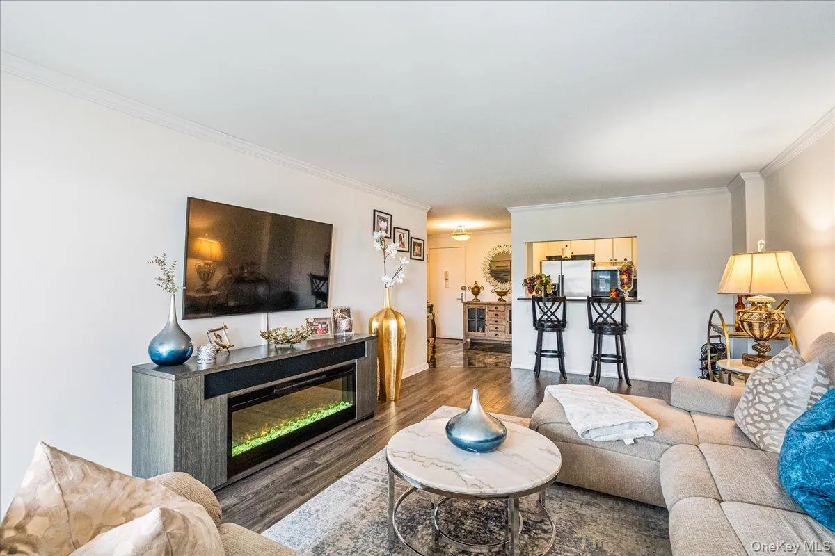 Living area featuring ornamental molding, wood finished floors, and a glass covered fireplace Living area featuring ornamental molding, wood finished floors, and a glass covered fireplace
