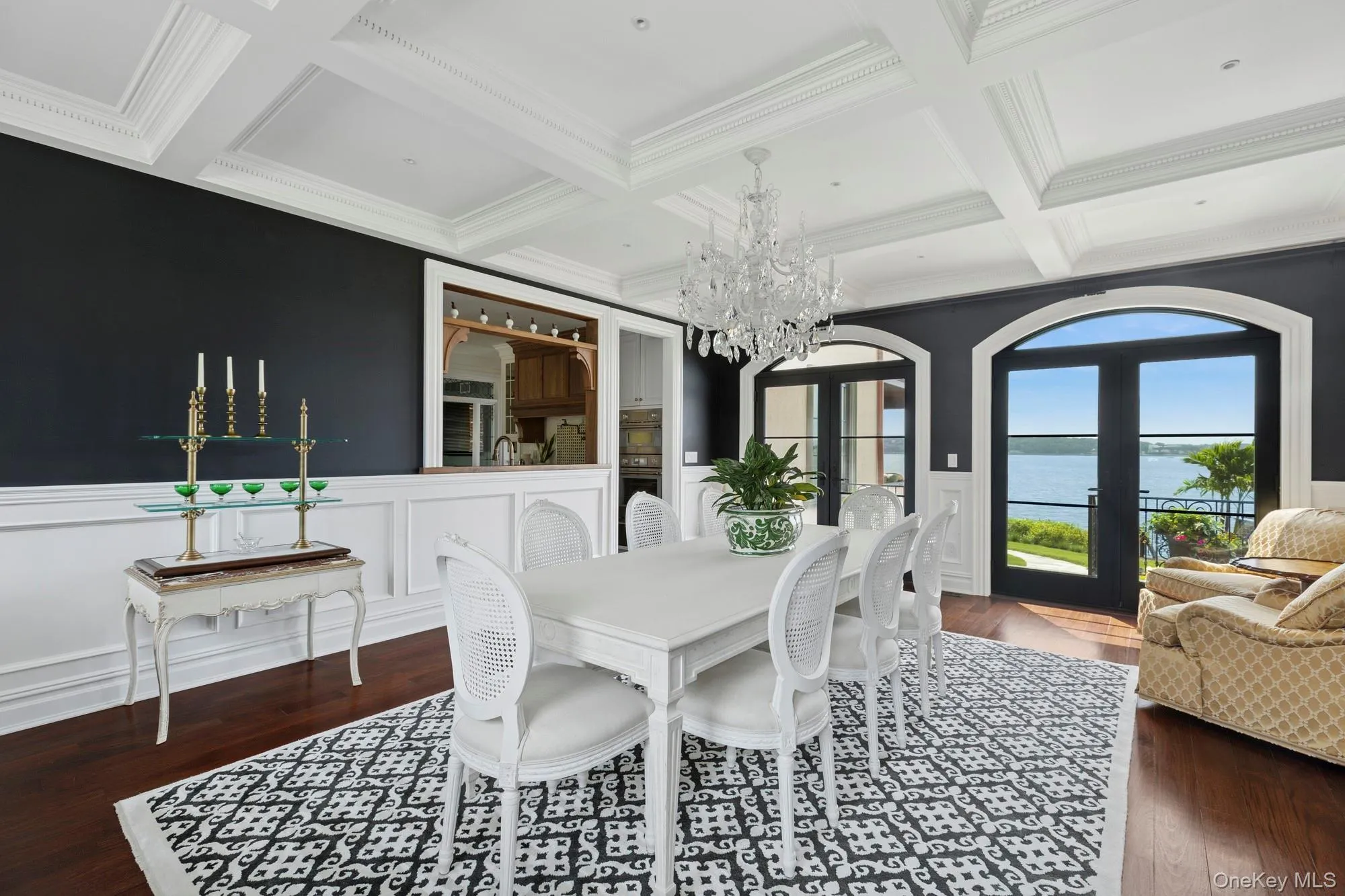 Dining space featuring wainscoting, french doors, a water view, dark wood-style floors, and crown molding Dining space featuring wainscoting, french doors, a water view, dark wood-style floors, and crown molding