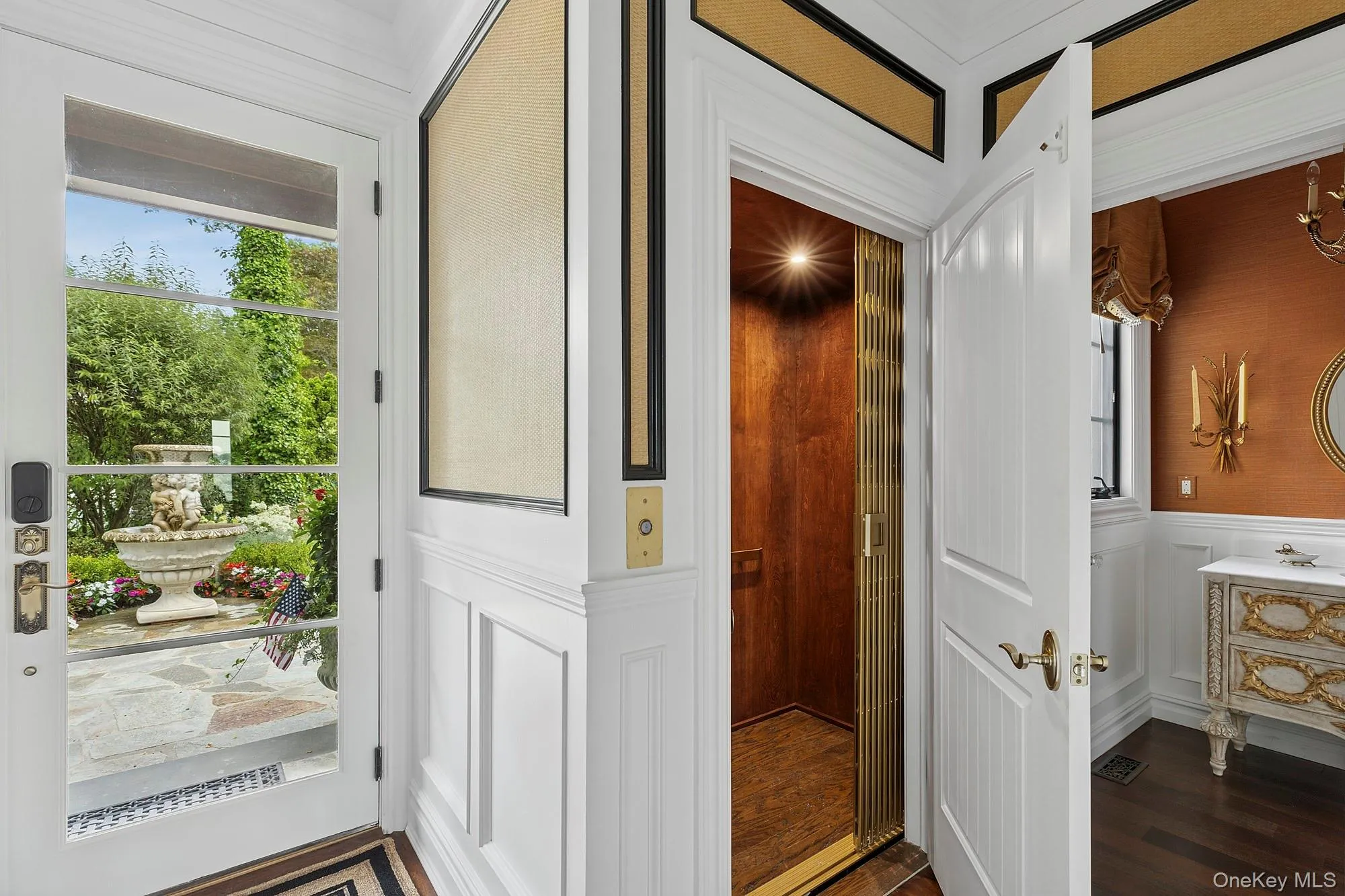 Hallway featuring a decorative wall, dark wood-style floors, elevator, and a wainscoted wall Hallway featuring a decorative wall, dark wood-style floors, elevator, and a wainscoted wall