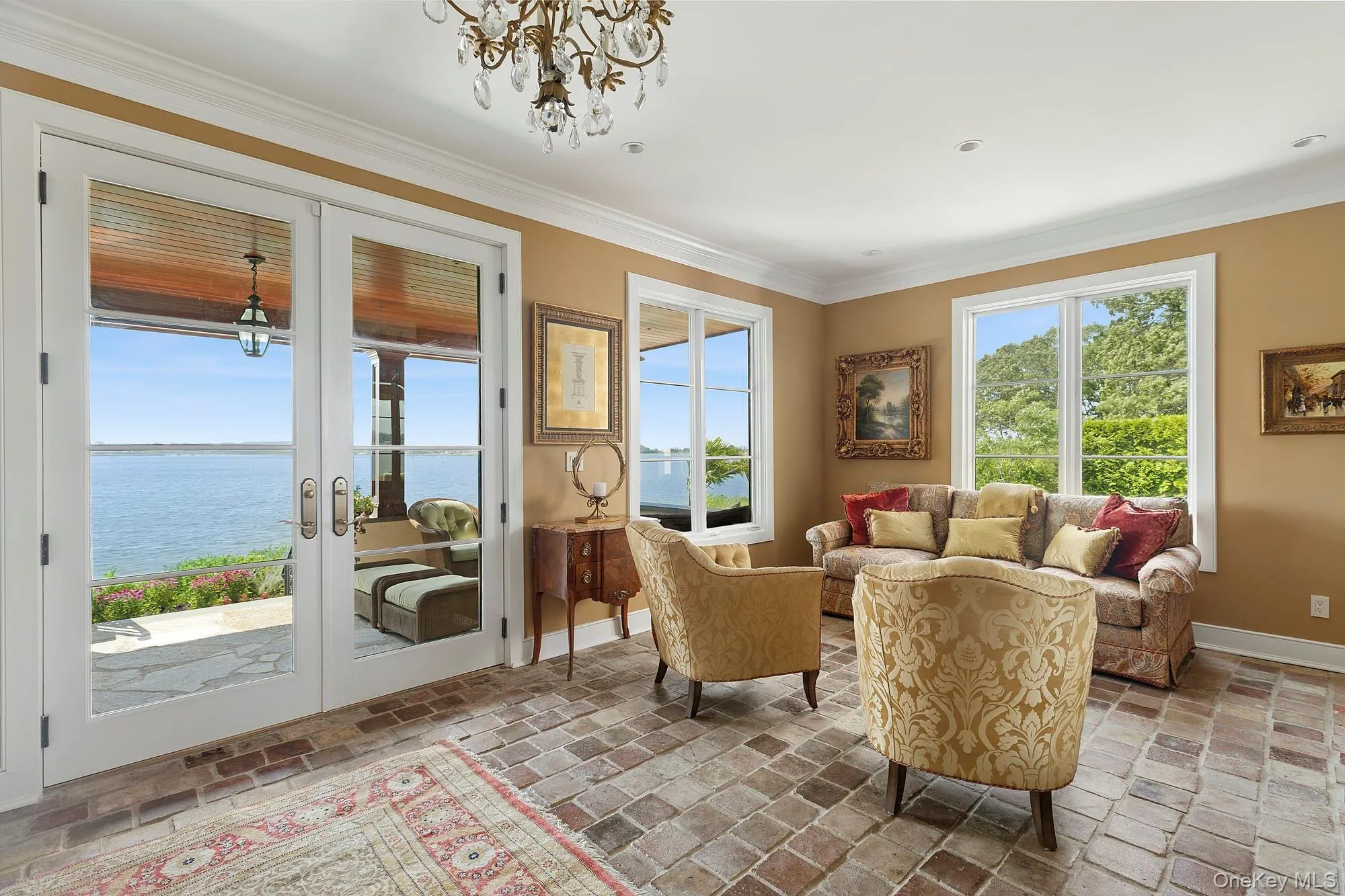 Sitting room with ornamental molding, french doors, a water view, a chandelier, and brick floors Sitting room with ornamental molding, french doors, a water view, a chandelier, and brick floors