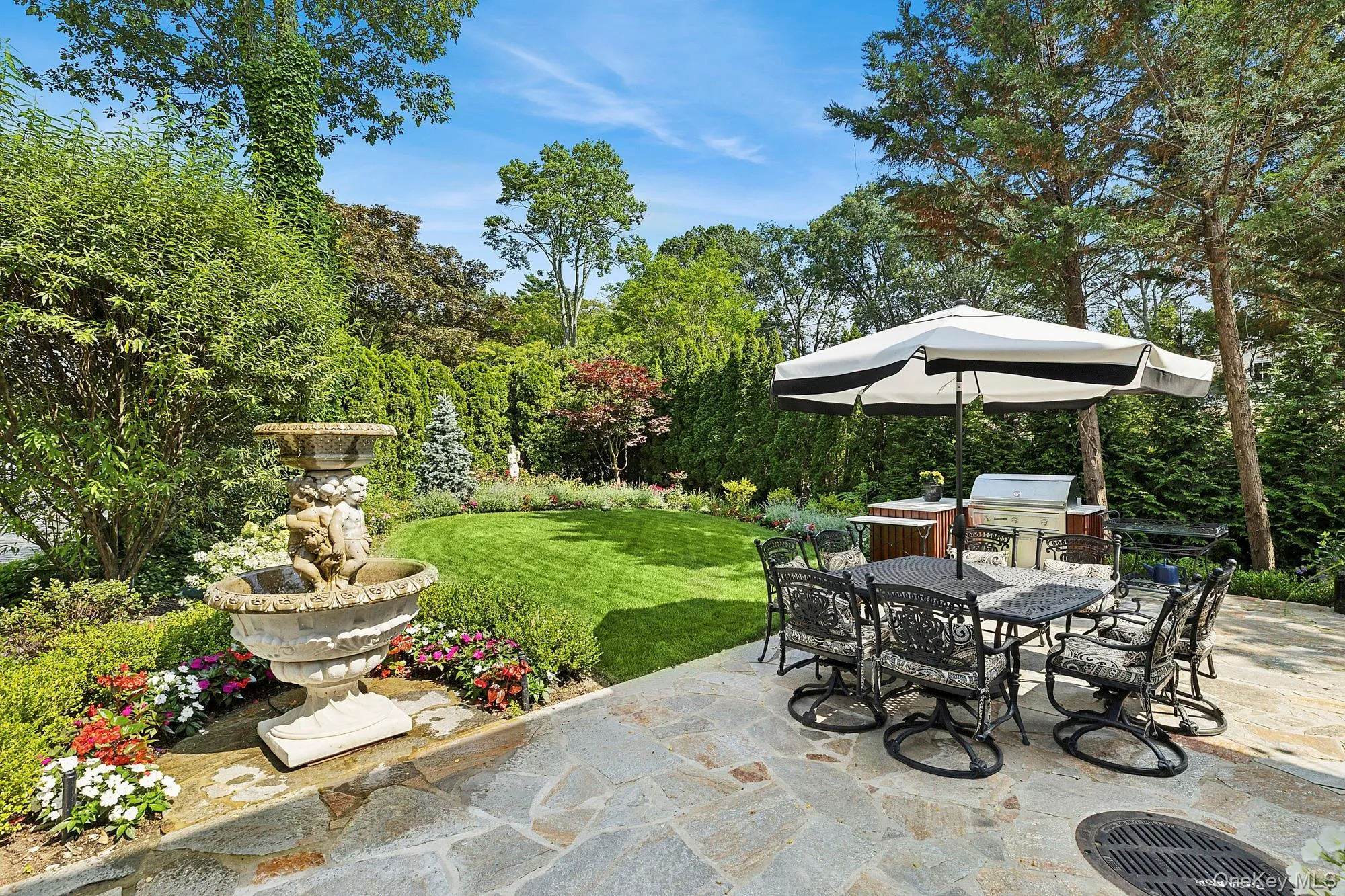 View of patio featuring outdoor dining space, an outdoor kitchen, and view of wooded area View of patio featuring outdoor dining space, an outdoor kitchen, and view of wooded area