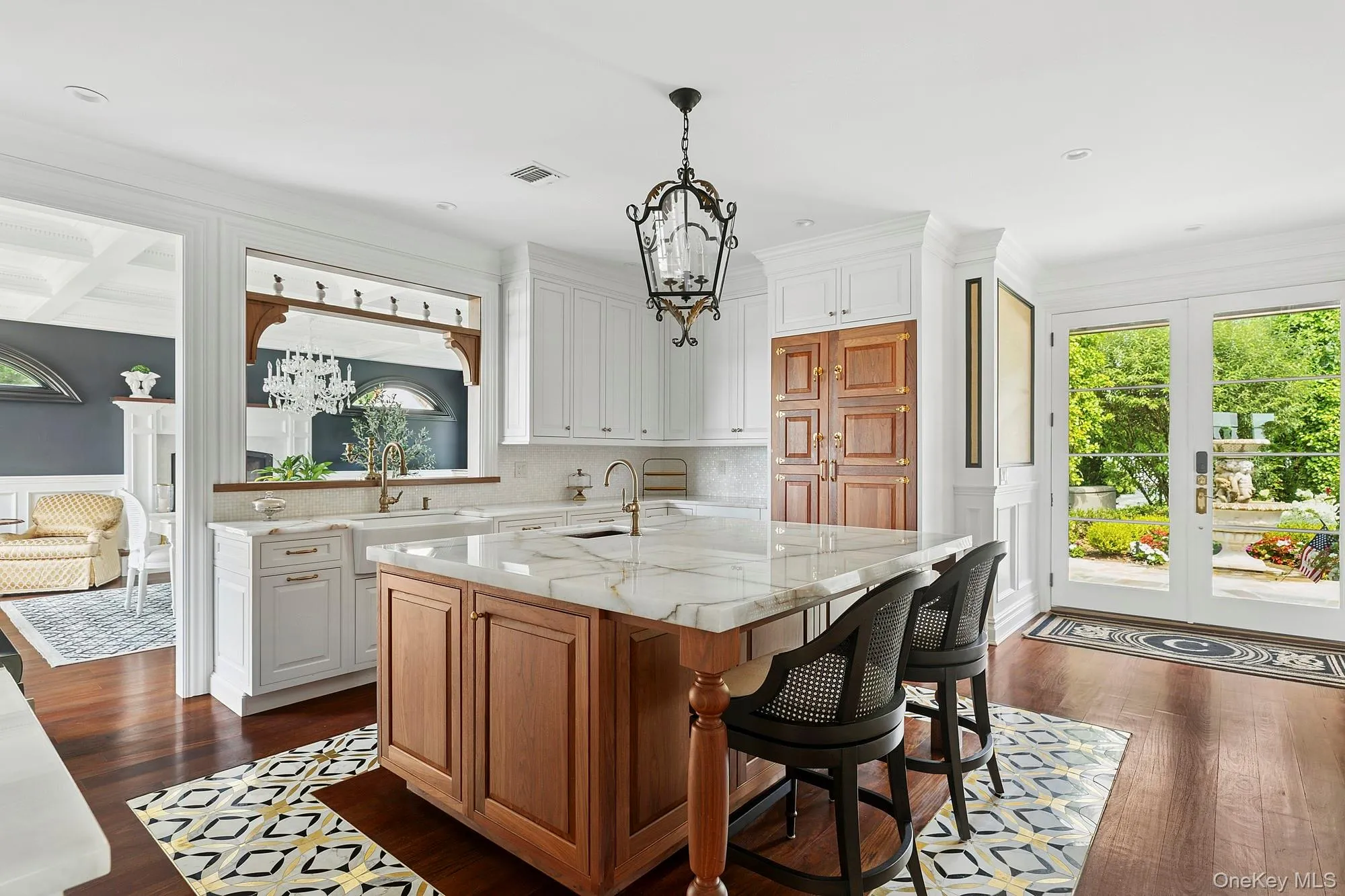 Kitchen featuring a chandelier, brown cabinetry, light stone counters, a breakfast bar area, and dark wood-type flooring Kitchen featuring a chandelier, brown cabinetry, light stone counters, a breakfast bar area, and dark wood-type flooring