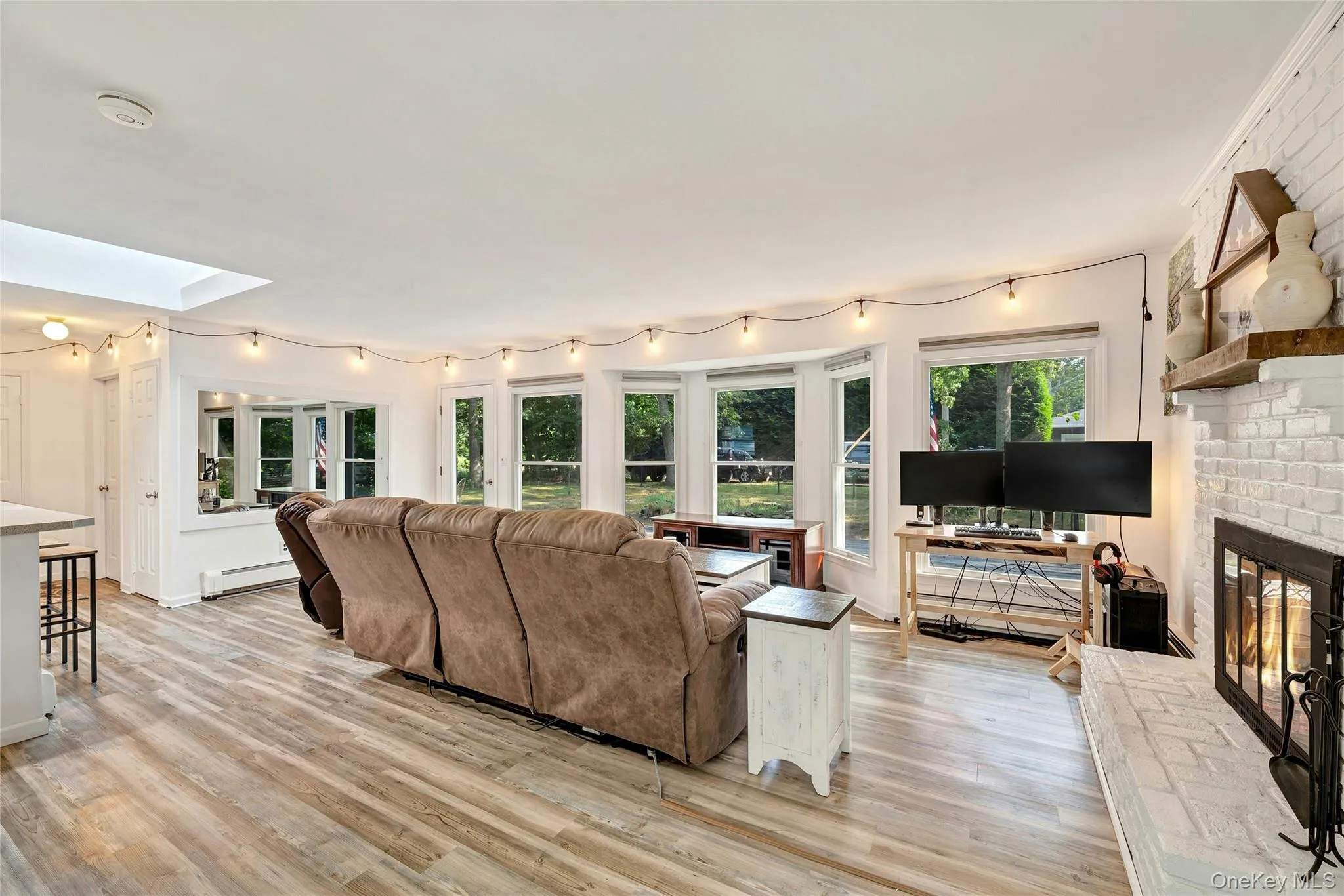 Living room with a fireplace, Full front wall of oversized windows and vinyl wide plank floors. Living room with a fireplace, Full front wall of oversized windows and vinyl wide plank floors.