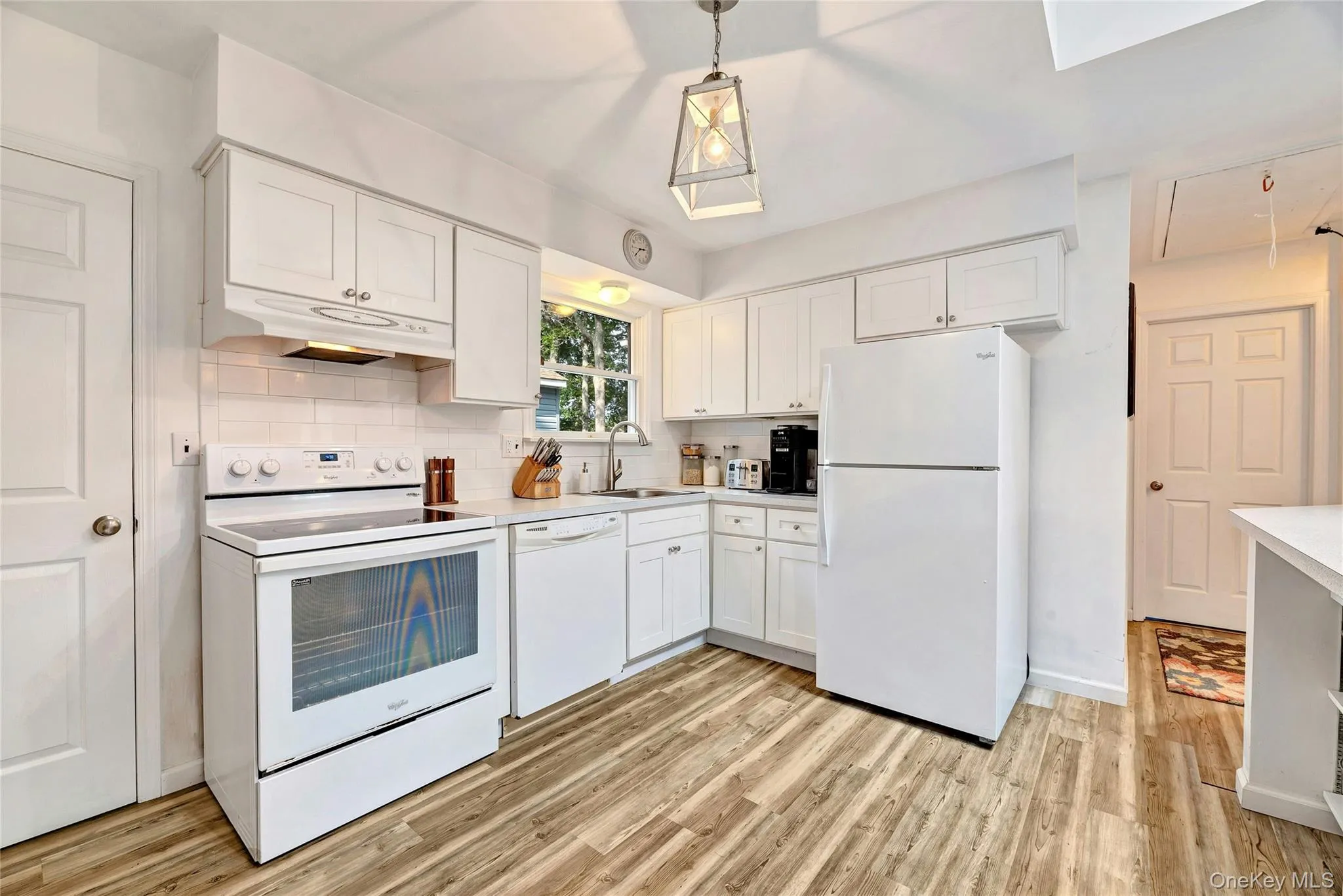 Kitchen with white appliances, white cabinetry, and subway tile backsplash. Kitchen with white appliances, white cabinetry, and subway tile backsplash.