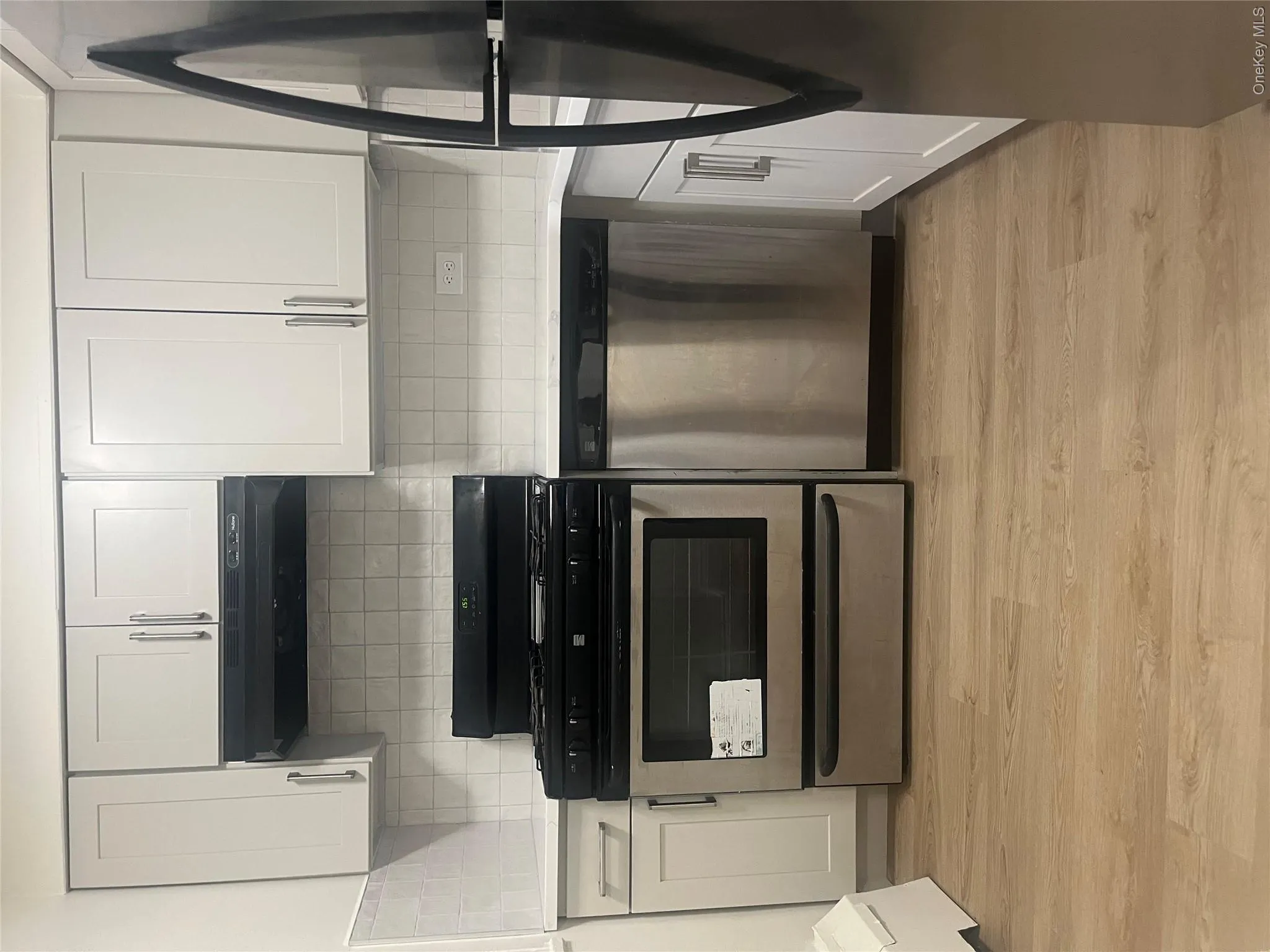 Kitchen with black range oven, stainless steel dishwasher, fridge, extractor fan, and light wood finished floors Kitchen with black range oven, stainless steel dishwasher, fridge, extractor fan, and light wood finished floors