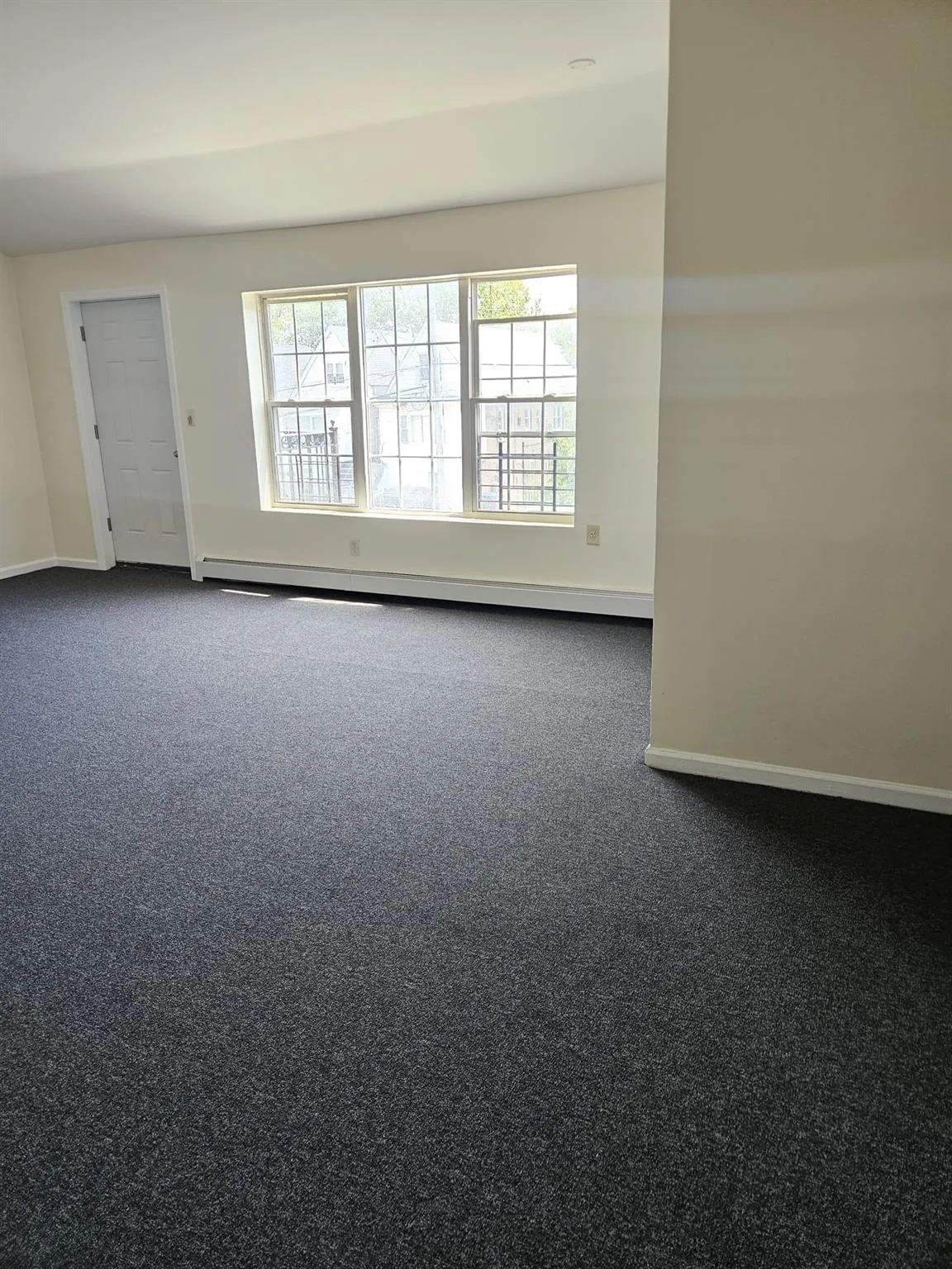 Empty room with dark carpet and a baseboard heating unit Empty room with dark carpet and a baseboard heating unit