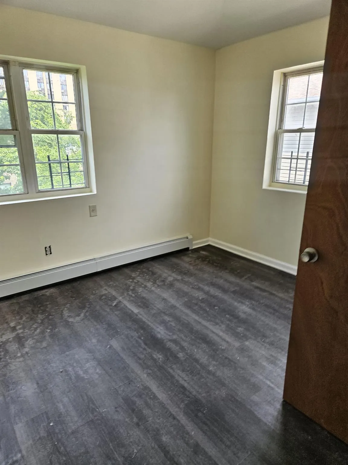 Spare room featuring a baseboard heating unit and dark wood-type flooring Spare room featuring a baseboard heating unit and dark wood-type flooring