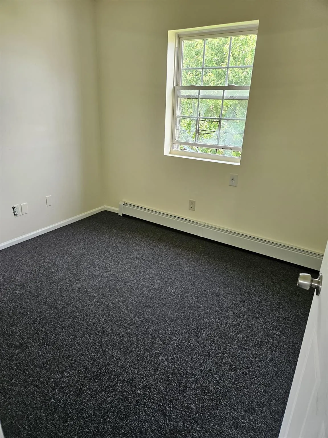Unfurnished room featuring baseboard heating and dark colored carpet Unfurnished room featuring baseboard heating and dark colored carpet