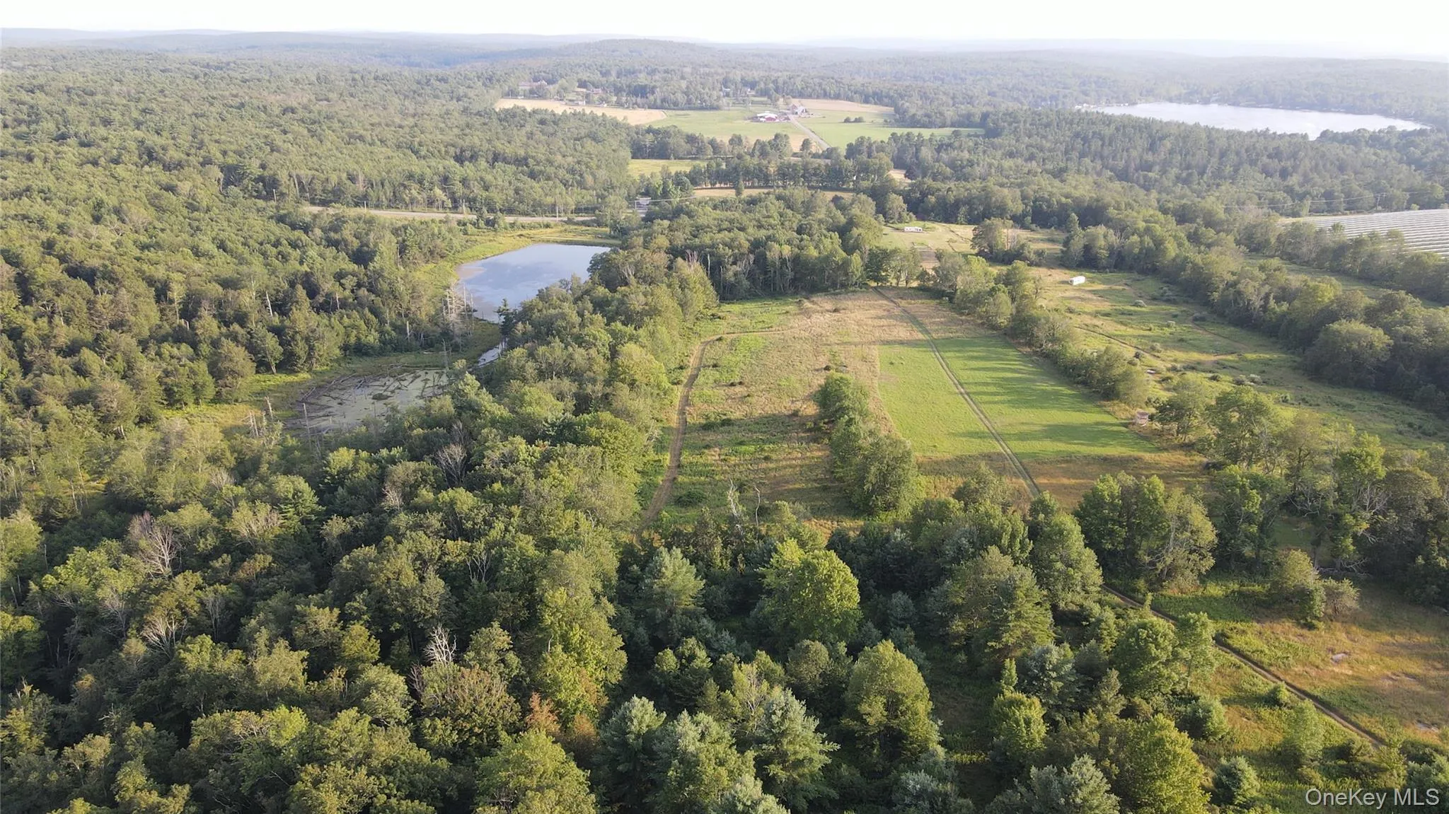 Aerial overview of property's location featuring a nearby body of water and a heavily wooded area Aerial overview of property's location featuring a nearby body of water and a heavily wooded area