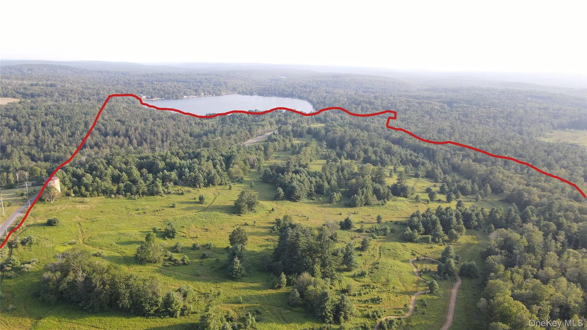 Aerial view of property and surrounding area featuring a forest and property parcel outlined Aerial view of property and surrounding area featuring a forest and property parcel outlined