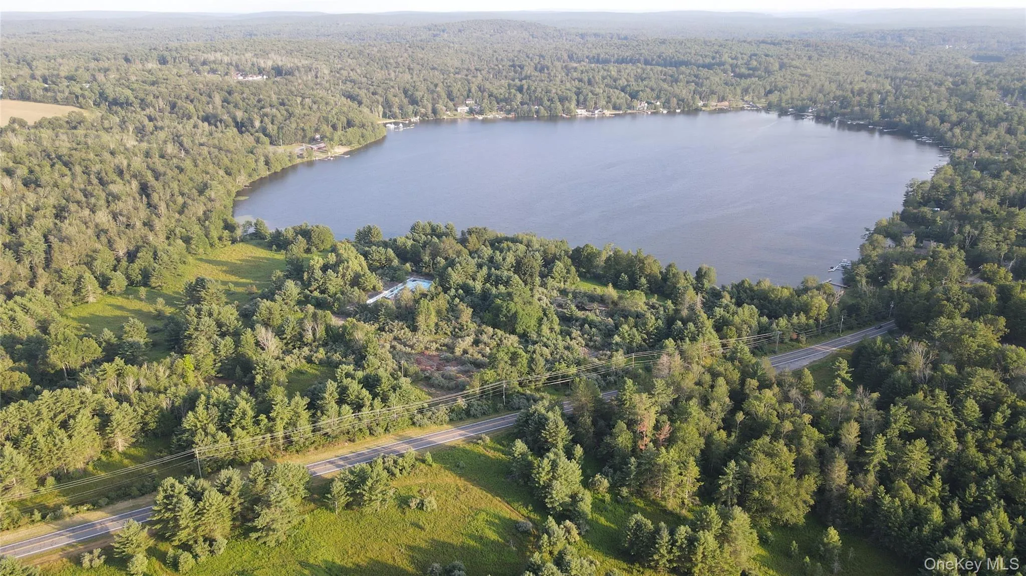 Aerial view of property and surrounding area with a forest and a large body of water Aerial view of property and surrounding area with a forest and a large body of water