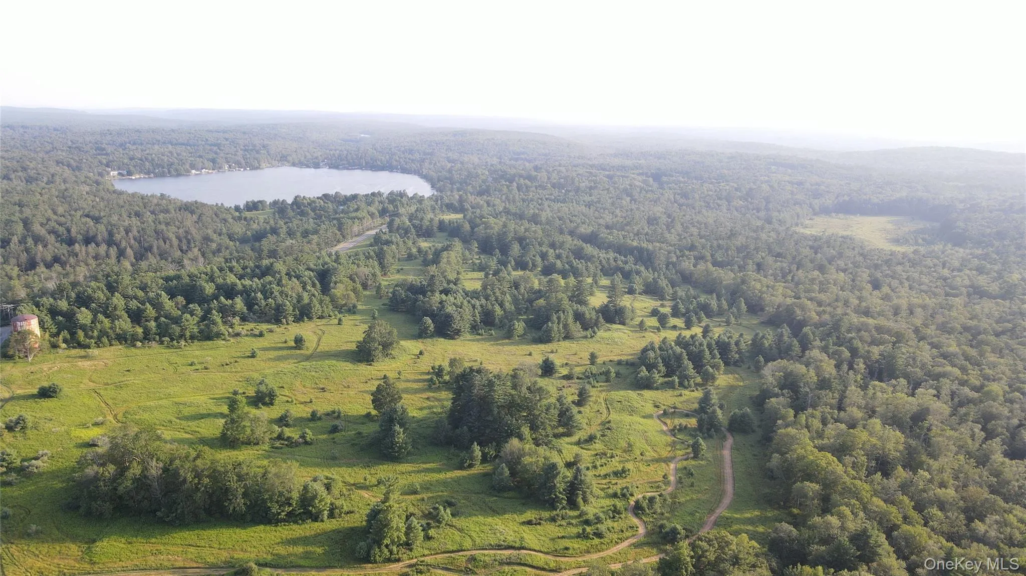 Aerial view of property and surrounding area featuring a heavily wooded area and a nearby body of water Aerial view of property and surrounding area featuring a heavily wooded area and a nearby body of water