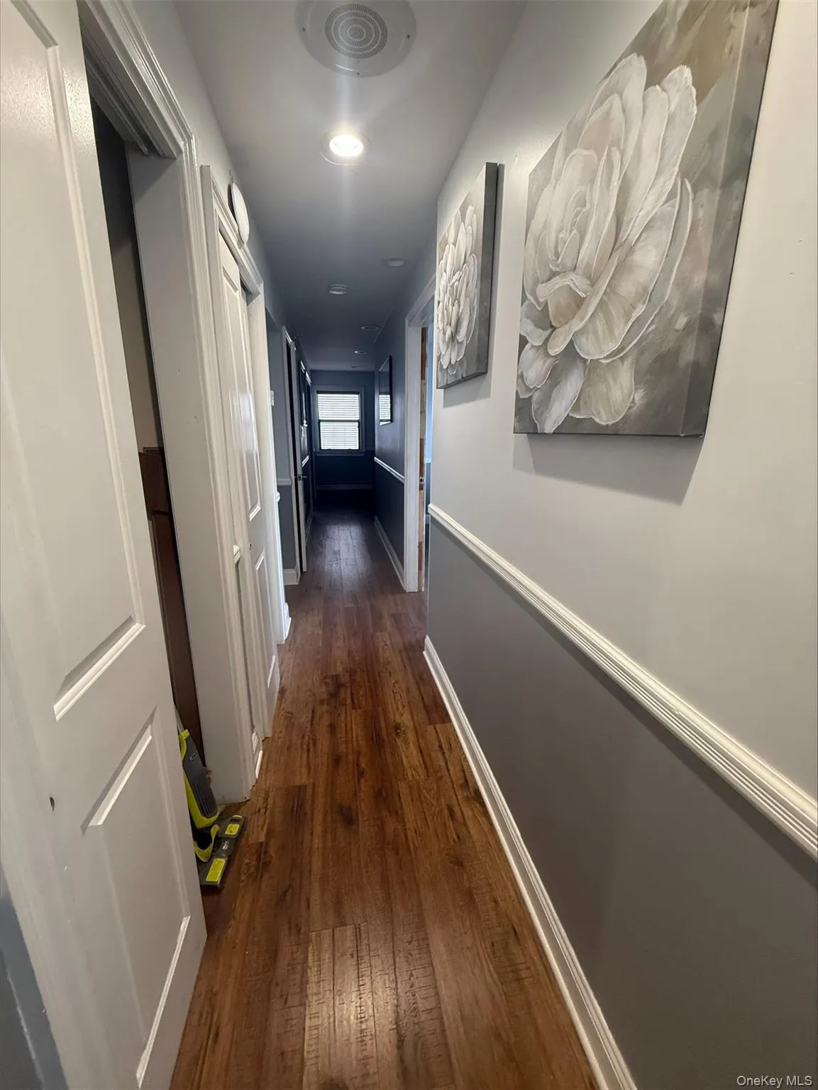 Corridor featuring dark wood-type flooring and baseboards Corridor featuring dark wood-type flooring and baseboards