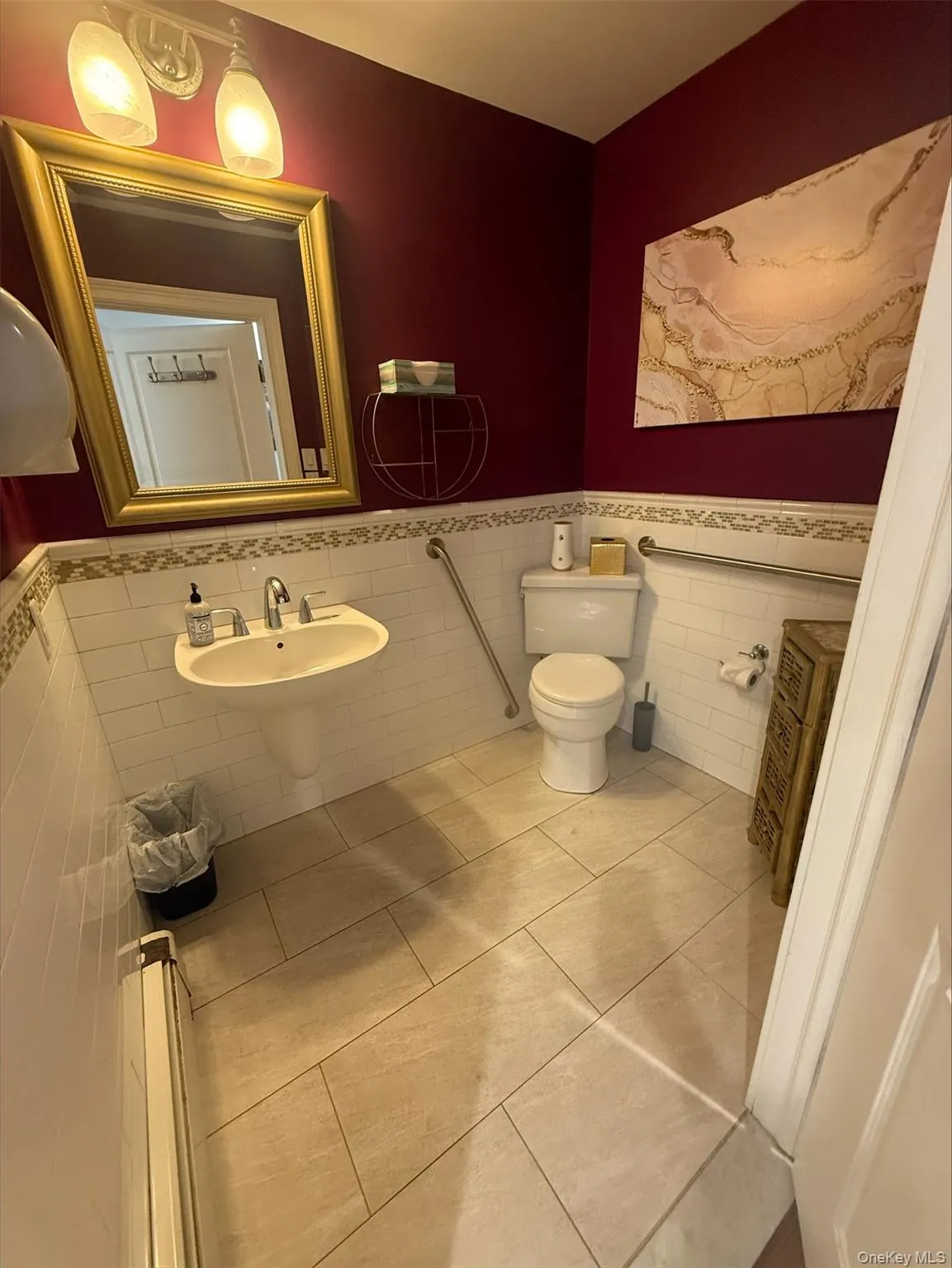 Half bathroom featuring wainscoting, tile walls, baseboard heating, and tile patterned floors Half bathroom featuring wainscoting, tile walls, baseboard heating, and tile patterned floors