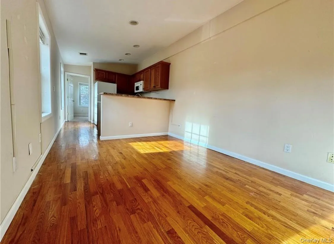 Unfurnished living room featuring light wood-style flooring and baseboards Unfurnished living room featuring light wood-style flooring and baseboards