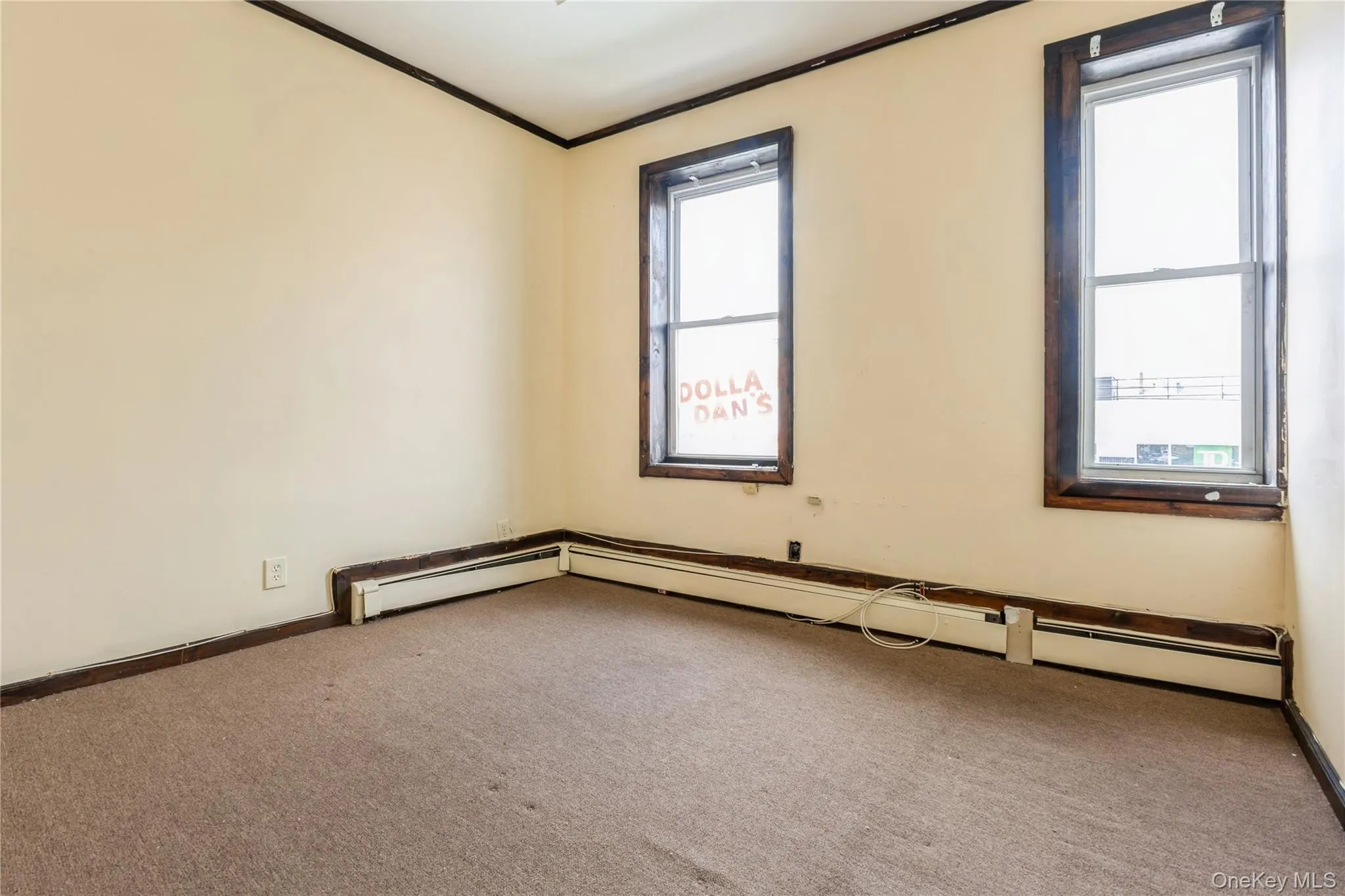 Carpeted empty room featuring crown molding, plenty of natural light, and a baseboard heating unit Carpeted empty room featuring crown molding, plenty of natural light, and a baseboard heating unit