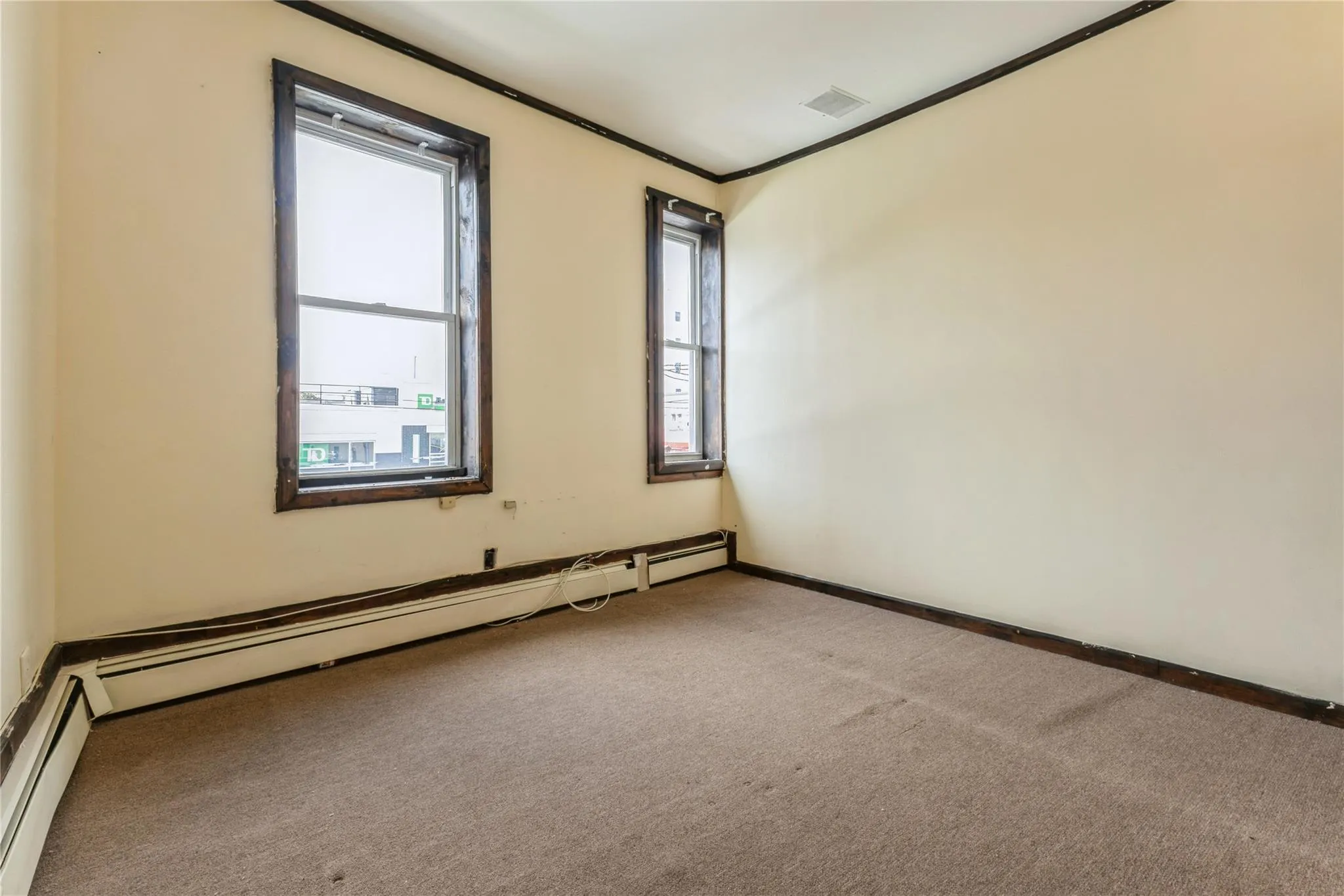 Carpeted spare room with ornamental molding and a baseboard heating unit Carpeted spare room with ornamental molding and a baseboard heating unit