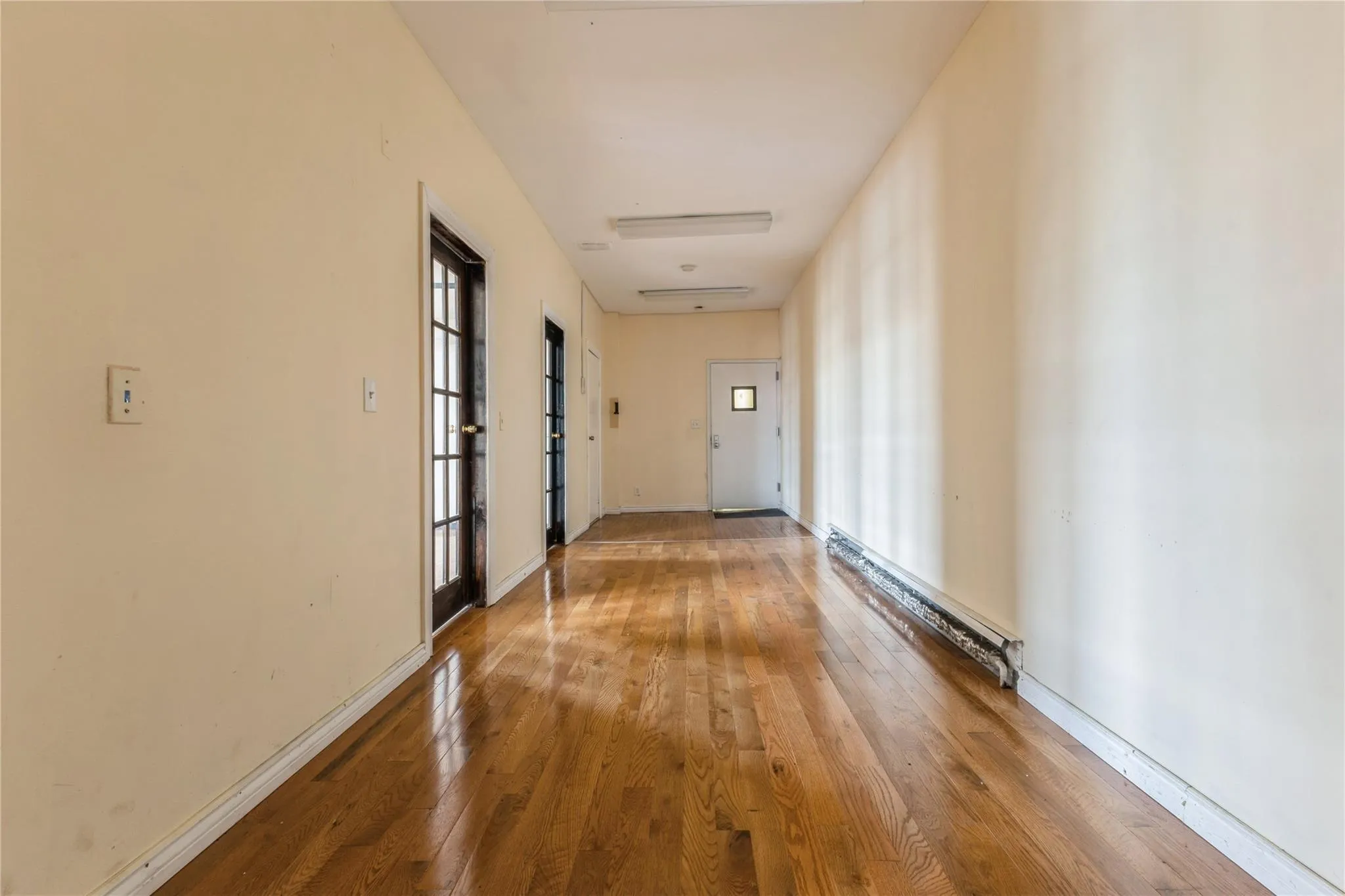 Hall with hardwood / wood-style flooring and a baseboard heating unit Hall with hardwood / wood-style flooring and a baseboard heating unit