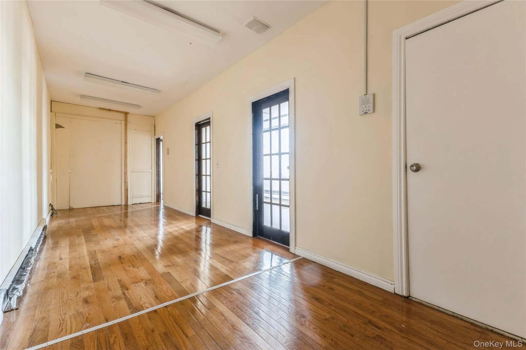 Unfurnished bedroom featuring hardwood / wood-style flooring and a baseboard heating unit Unfurnished bedroom featuring hardwood / wood-style flooring and a baseboard heating unit