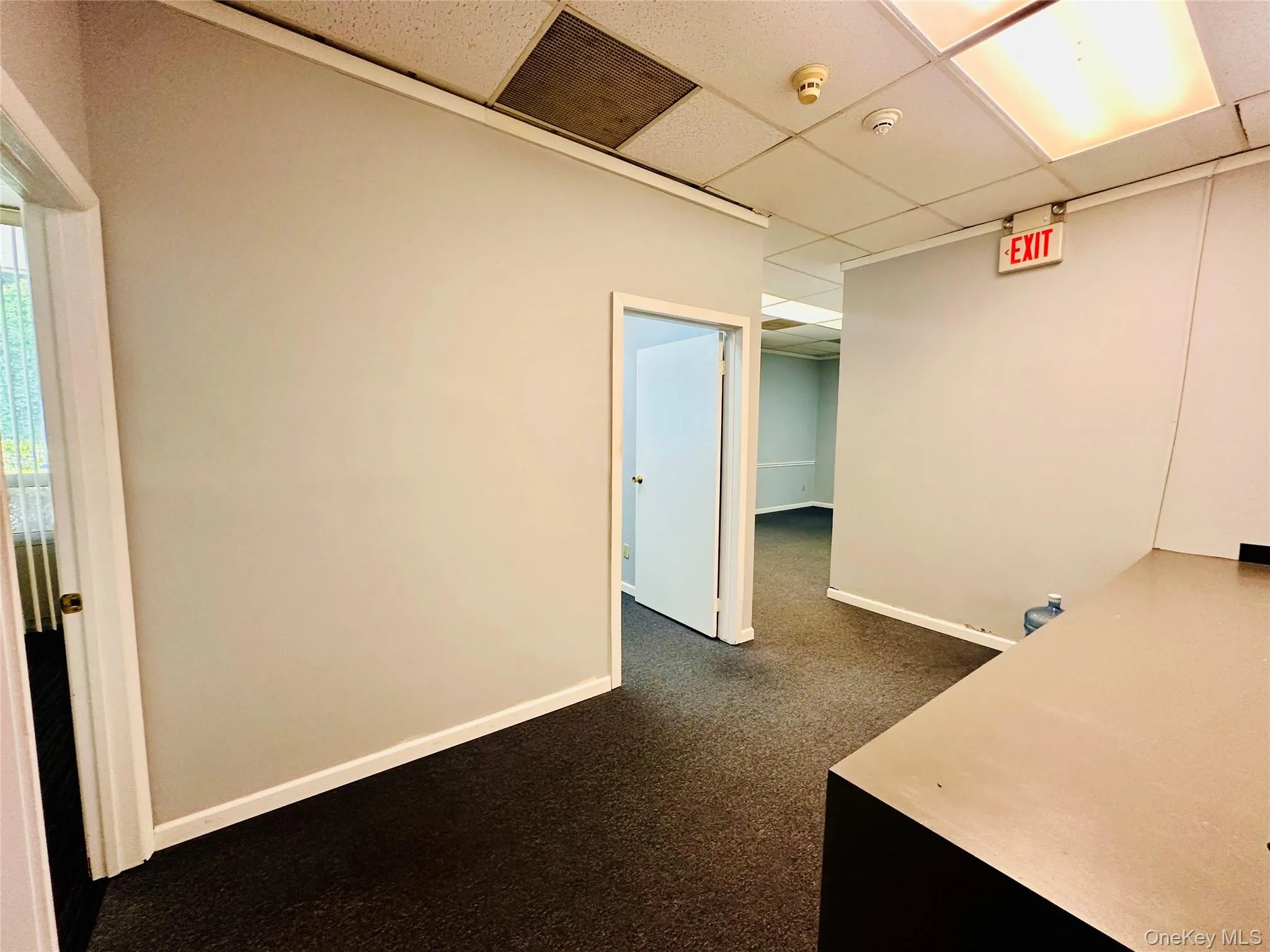 Unfurnished office with a drop ceiling and dark colored carpet Unfurnished office with a drop ceiling and dark colored carpet