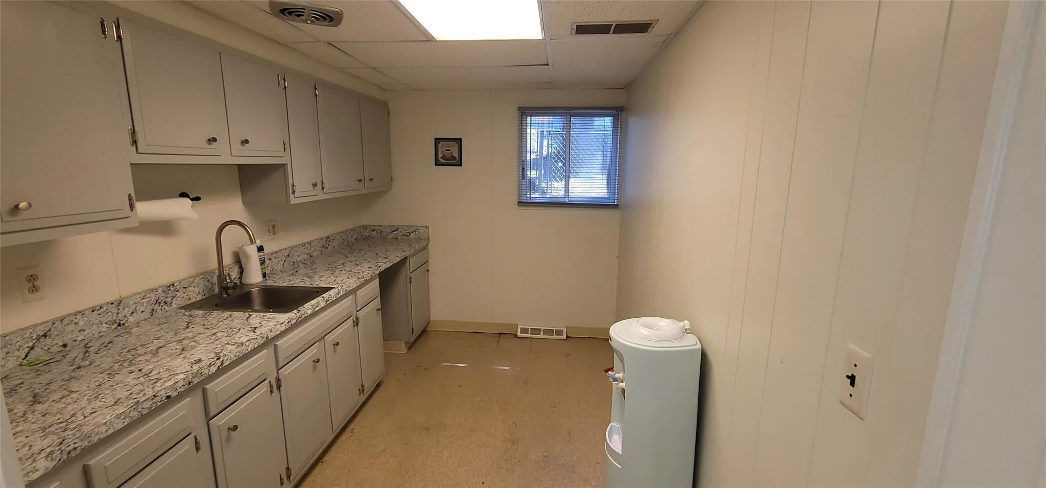 Kitchen featuring a sink and a paneled ceiling Kitchen featuring a sink and a paneled ceiling