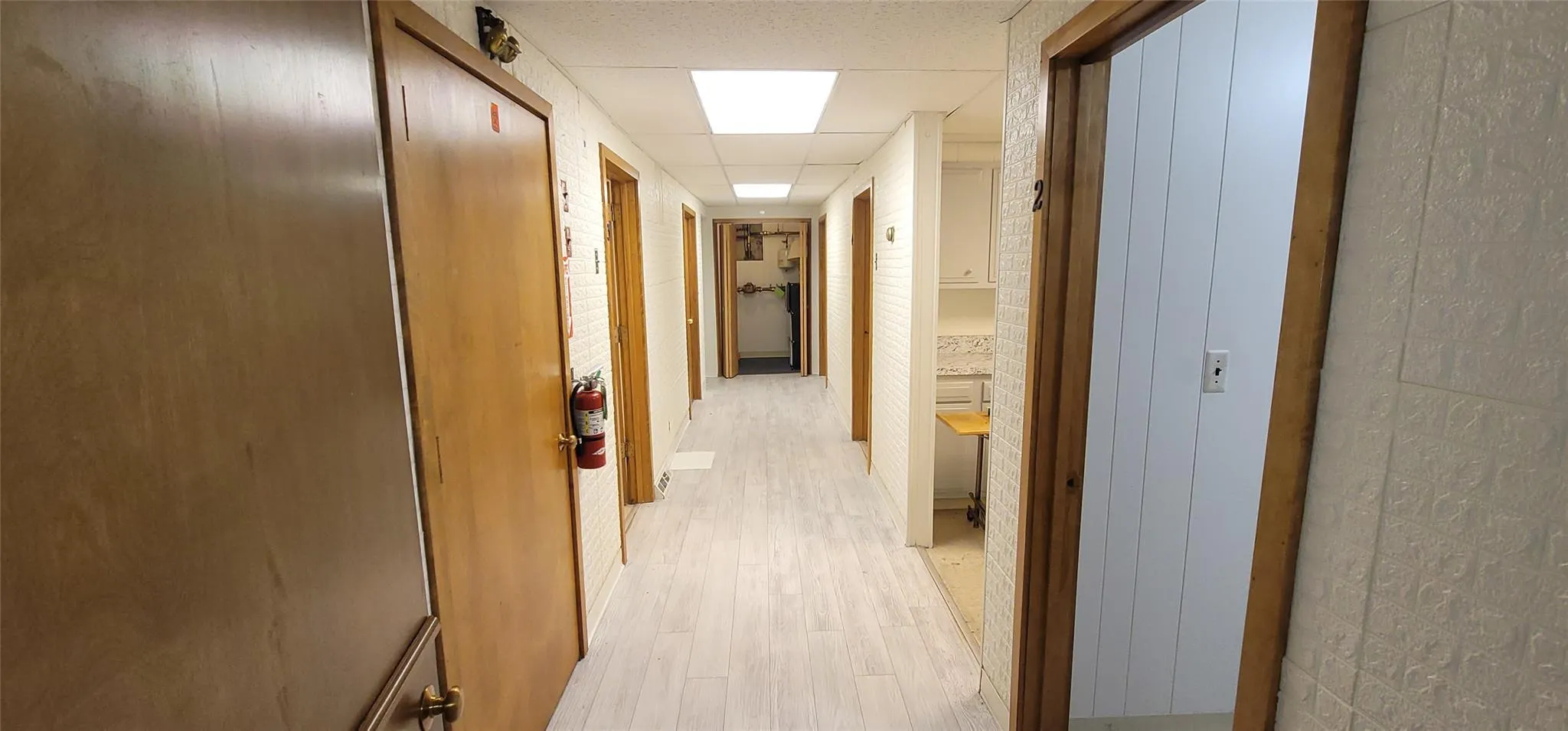 Corridor featuring a paneled ceiling and light wood-style flooring Corridor featuring a paneled ceiling and light wood-style flooring