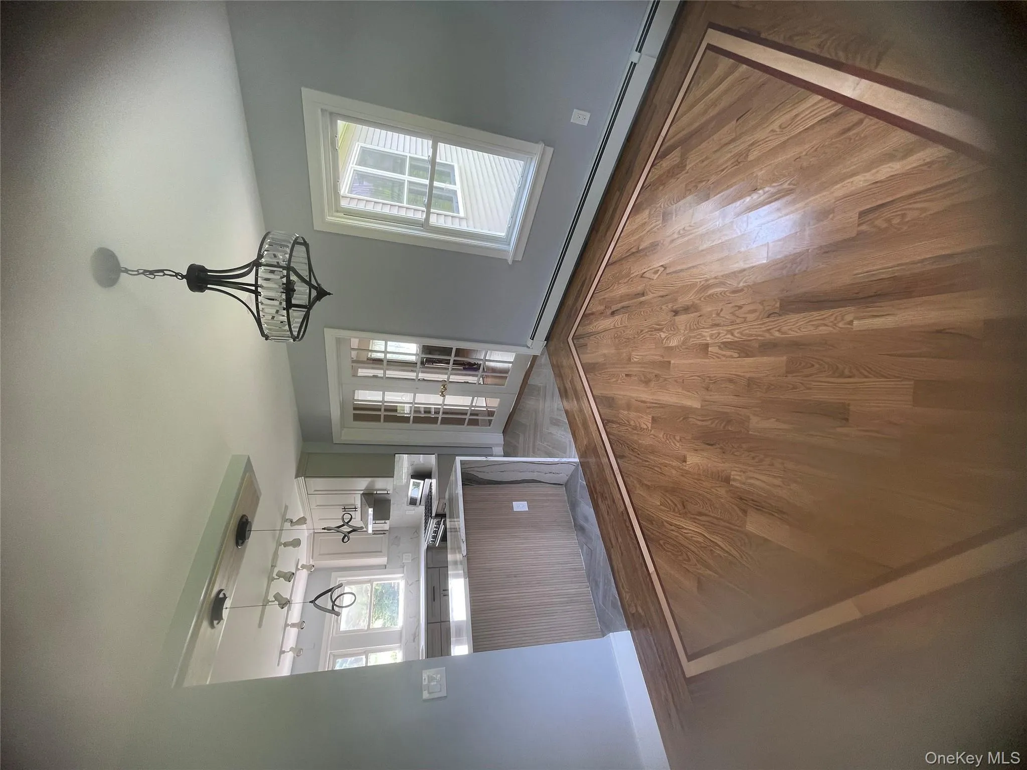 Kitchen with a baseboard heating unit, a chandelier, wood finished floors, range, and light countertops Kitchen with a baseboard heating unit, a chandelier, wood finished floors, range, and light countertops