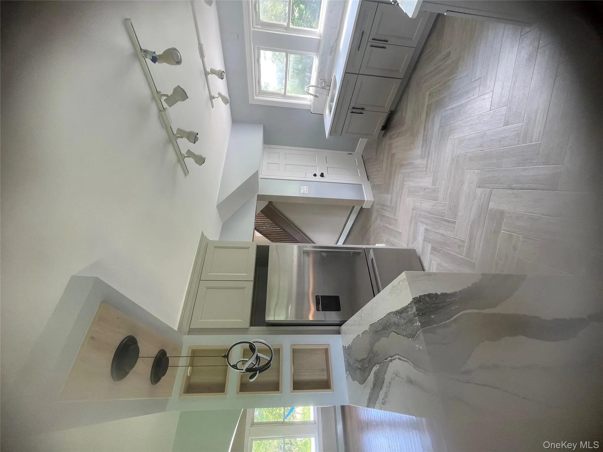 Kitchen featuring fridge, light stone countertops, a baseboard radiator, hanging light fixtures, and rail lighting Kitchen featuring fridge, light stone countertops, a baseboard radiator, hanging light fixtures, and rail lighting