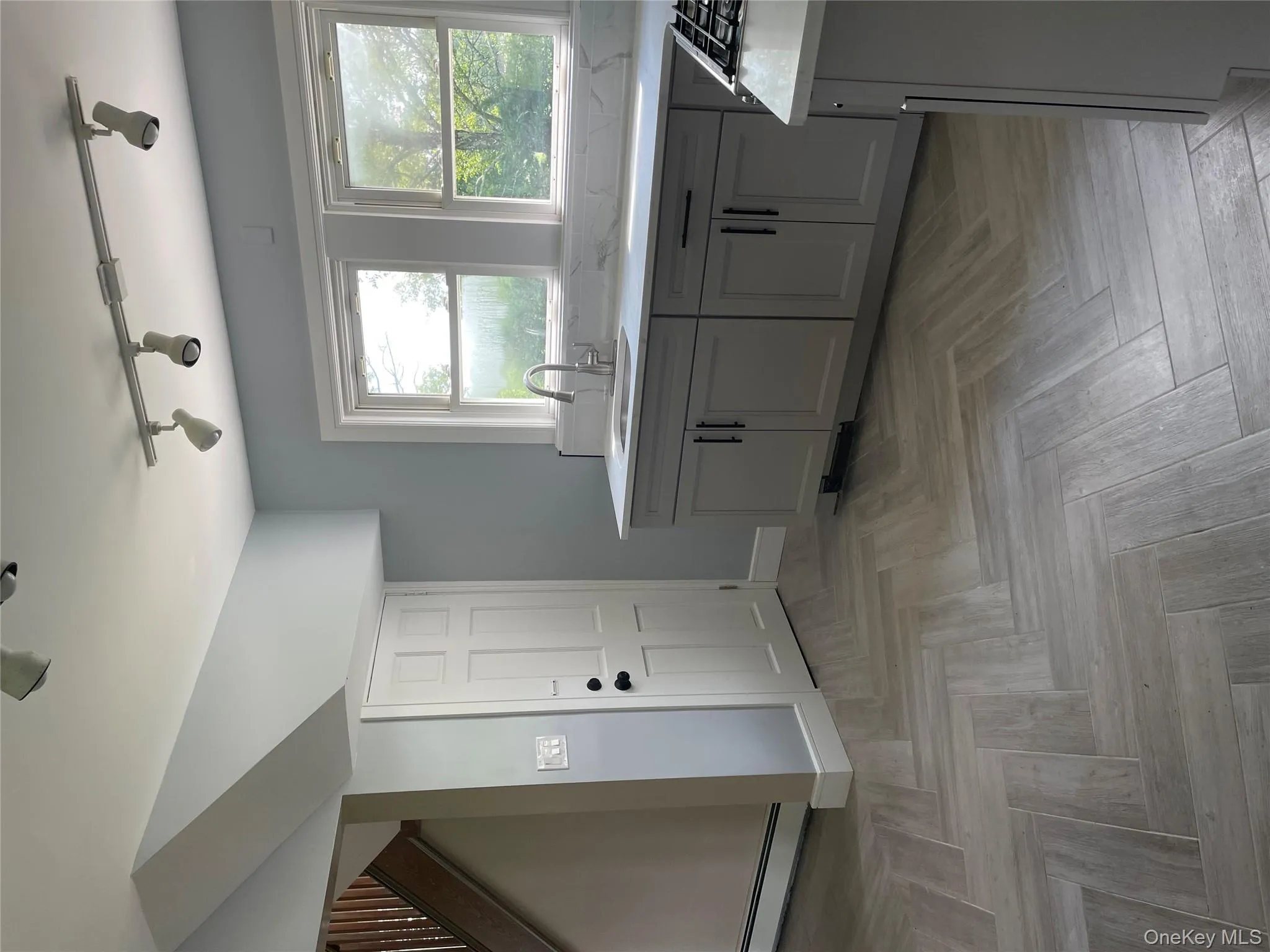 Kitchen with rail lighting, light countertops, baseboard heating, and healthy amount of natural light Kitchen with rail lighting, light countertops, baseboard heating, and healthy amount of natural light