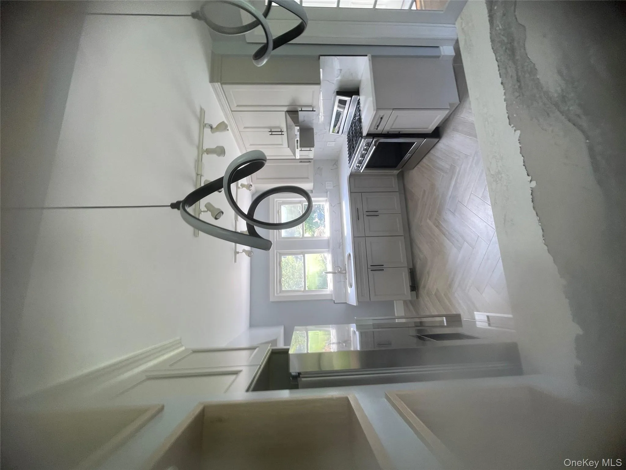 Kitchen with stove, light countertops, gray cabinets, fridge, and exhaust hood Kitchen with stove, light countertops, gray cabinets, fridge, and exhaust hood