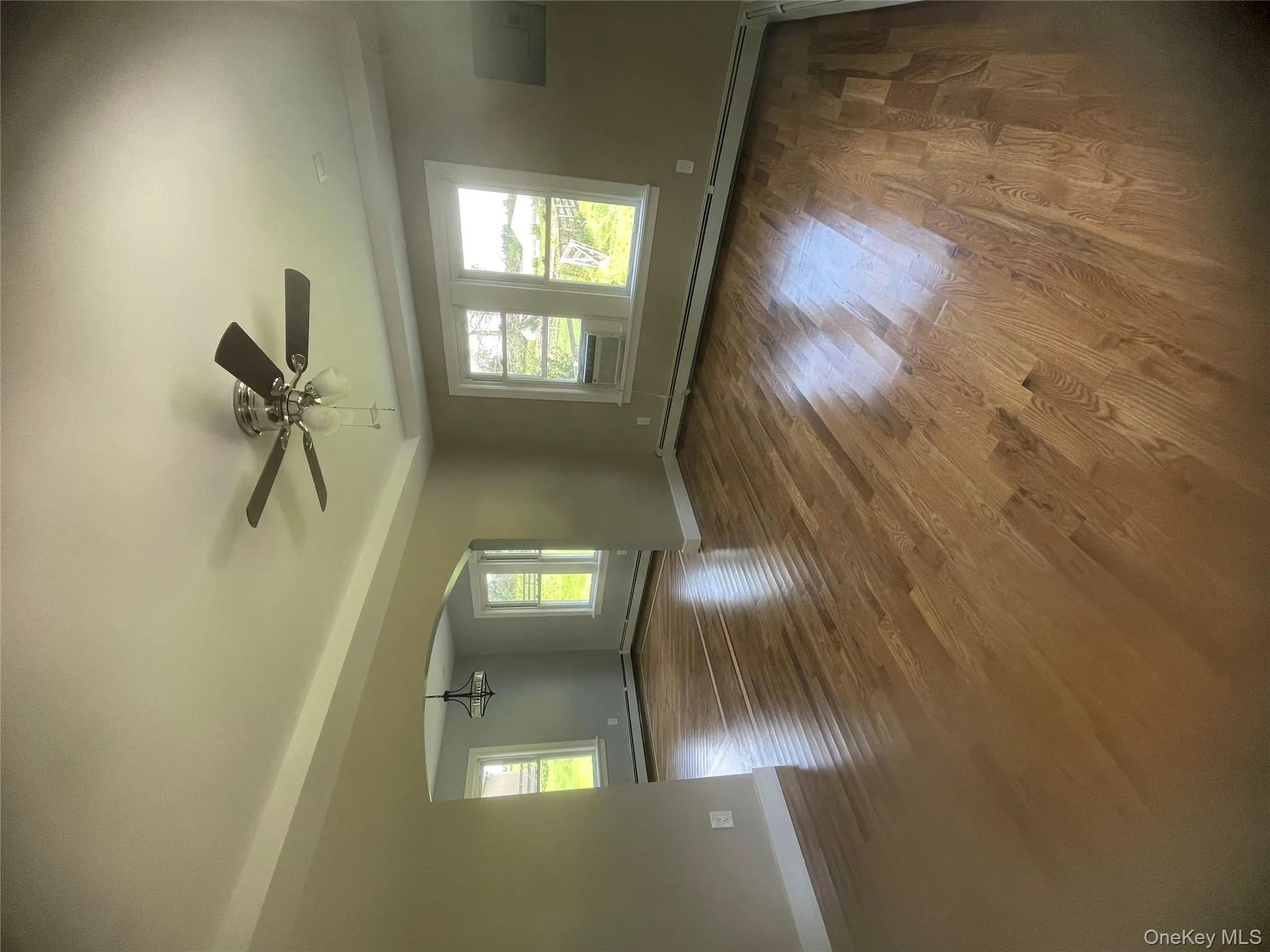 Unfurnished room with arched walkways, a ceiling fan, wood finished floors, and a baseboard radiator Unfurnished room with arched walkways, a ceiling fan, wood finished floors, and a baseboard radiator