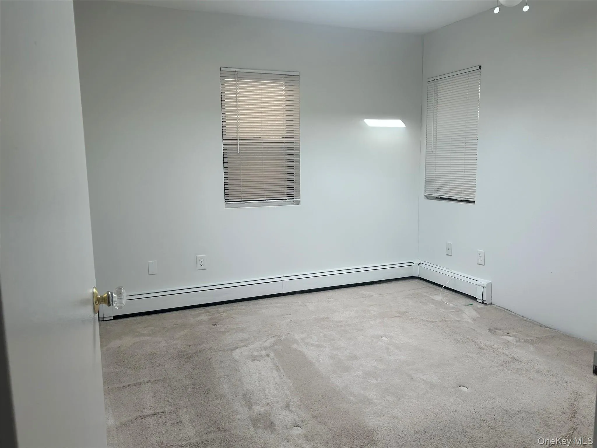 Spare room featuring carpet flooring and a baseboard heating unit Spare room featuring carpet flooring and a baseboard heating unit