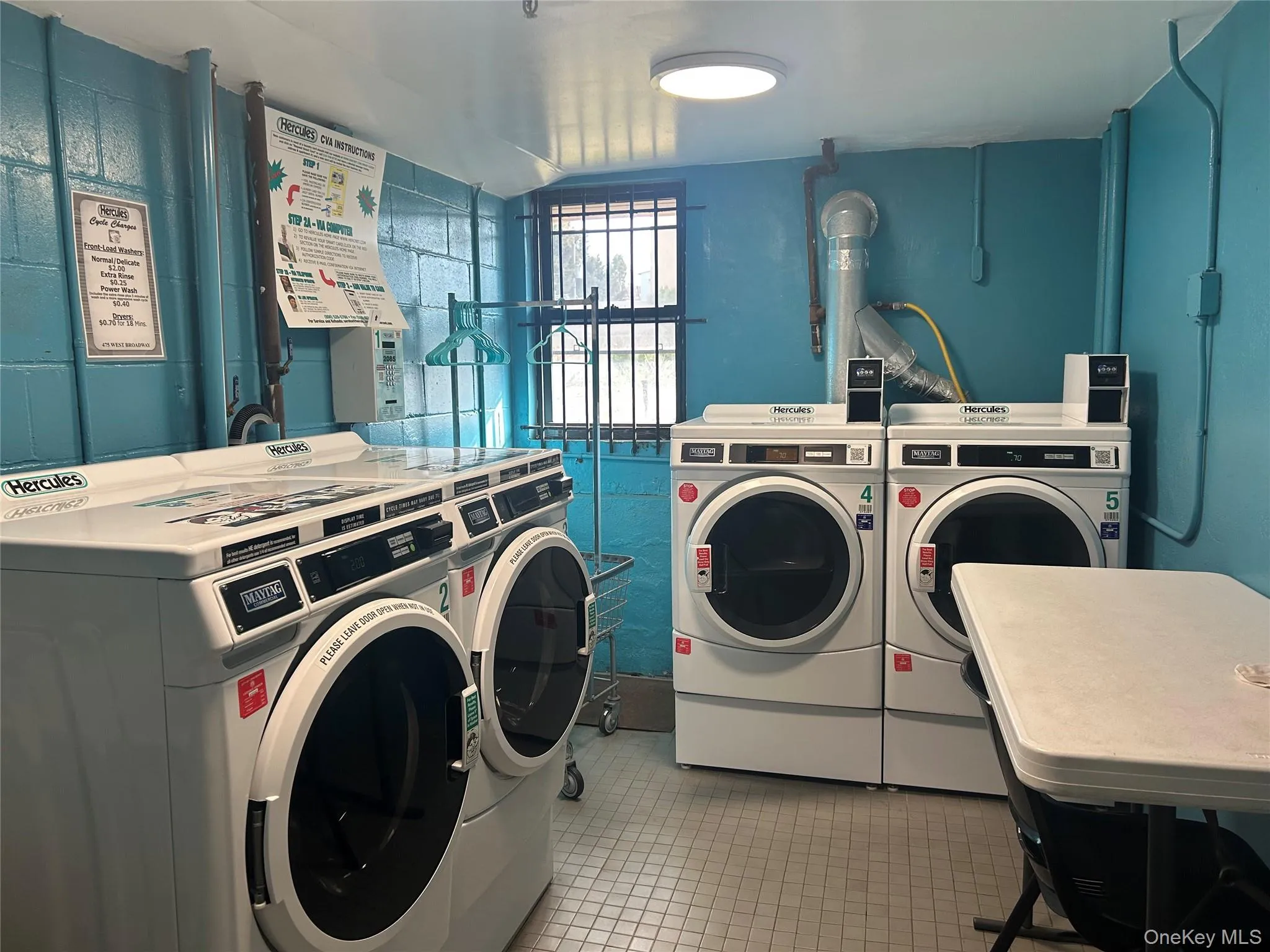 Communal laundry room with washing machine and dryer and light tile patterned floors Communal laundry room with washing machine and dryer and light tile patterned floors