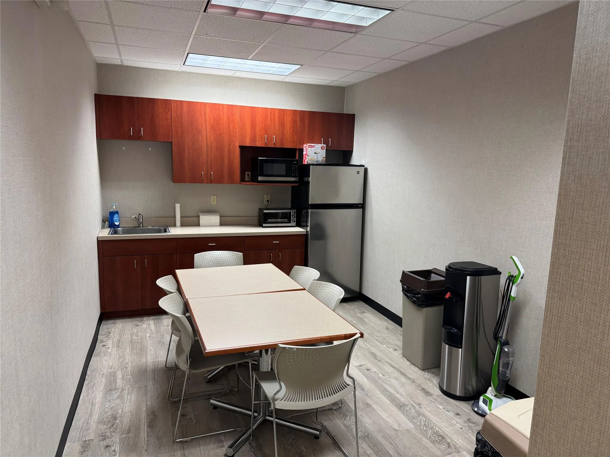 Kitchen featuring light wood finished floors, freestanding refrigerator, light countertops, and a paneled ceiling Kitchen featuring light wood finished floors, freestanding refrigerator, light countertops, and a paneled ceiling