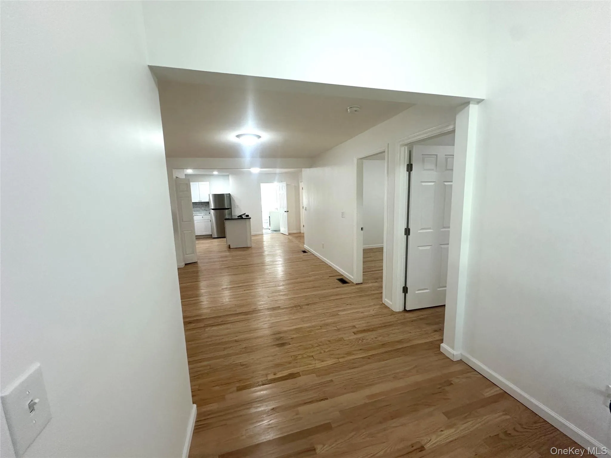 Hallway with light wood-style flooring and baseboards Hallway with light wood-style flooring and baseboards