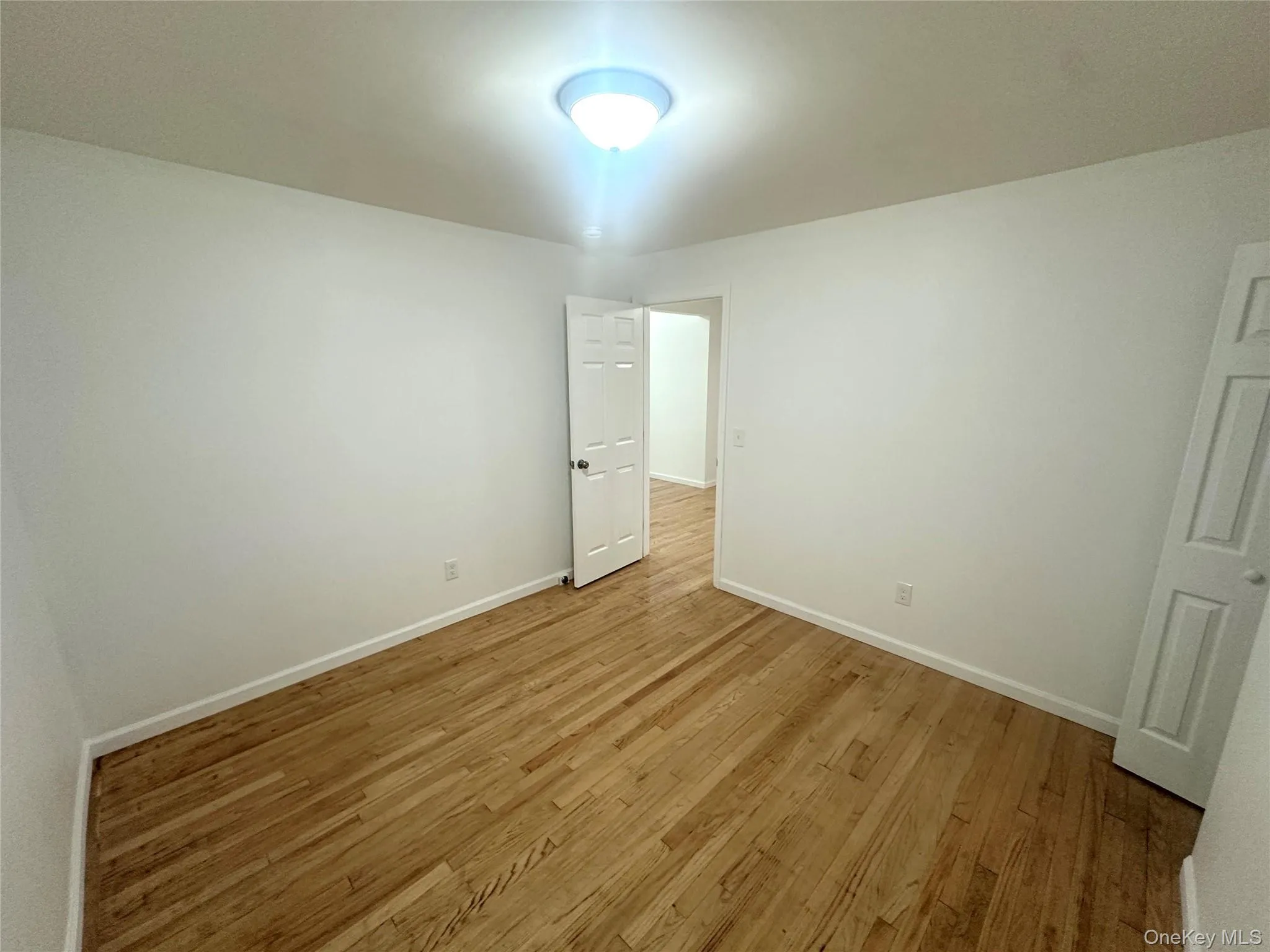 Unfurnished room with light wood-style floors and baseboards Unfurnished room with light wood-style floors and baseboards