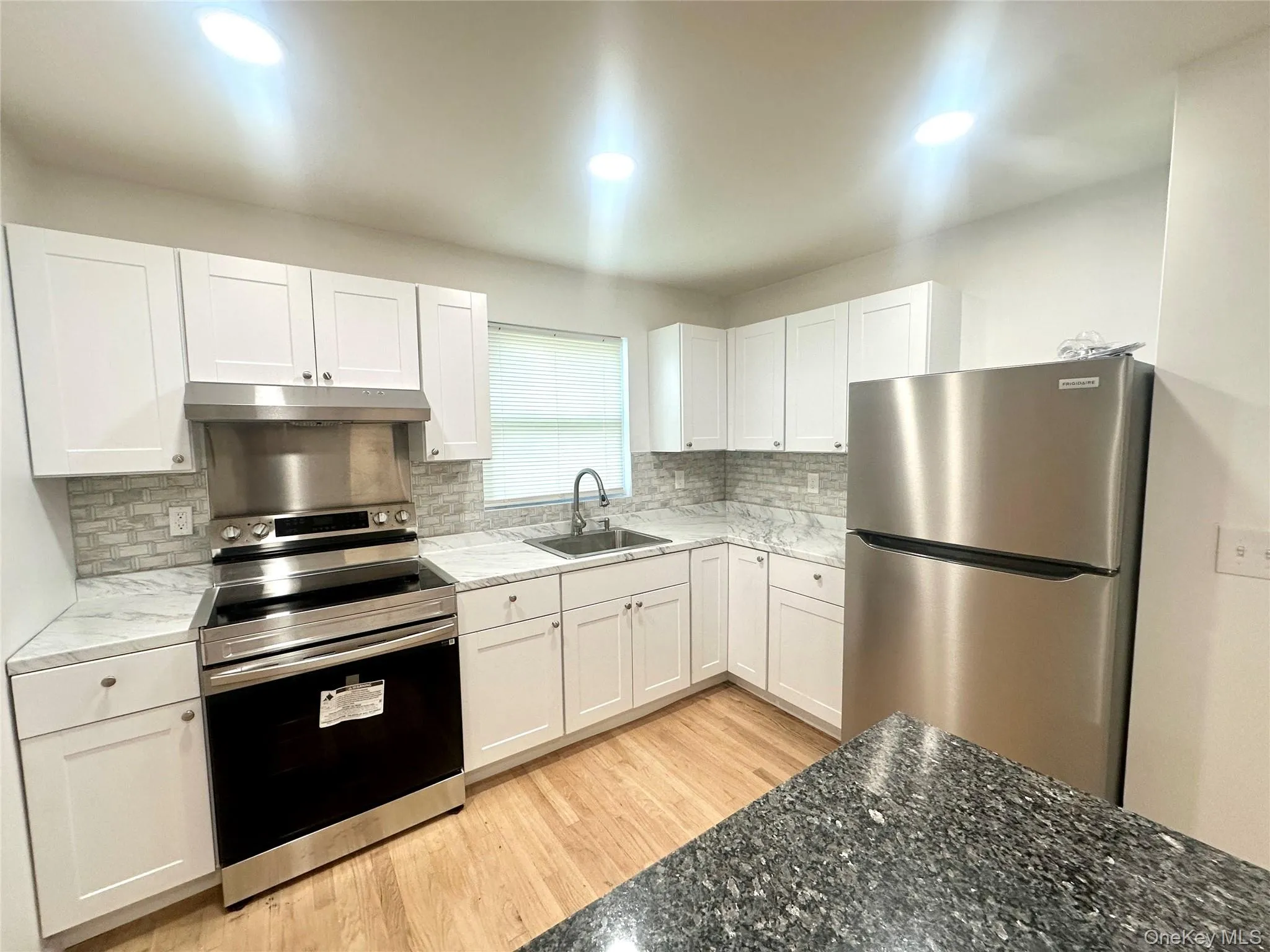Kitchen with stainless steel appliances, white cabinetry, dark stone counters, and recessed lighting Kitchen with stainless steel appliances, white cabinetry, dark stone counters, and recessed lighting