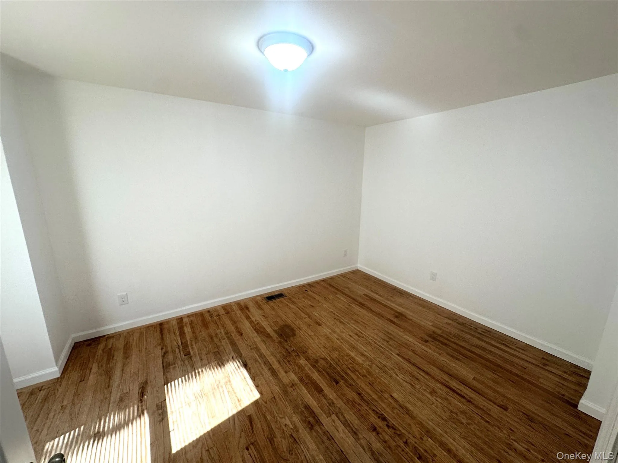 Empty room featuring wood finished floors and baseboards Empty room featuring wood finished floors and baseboards