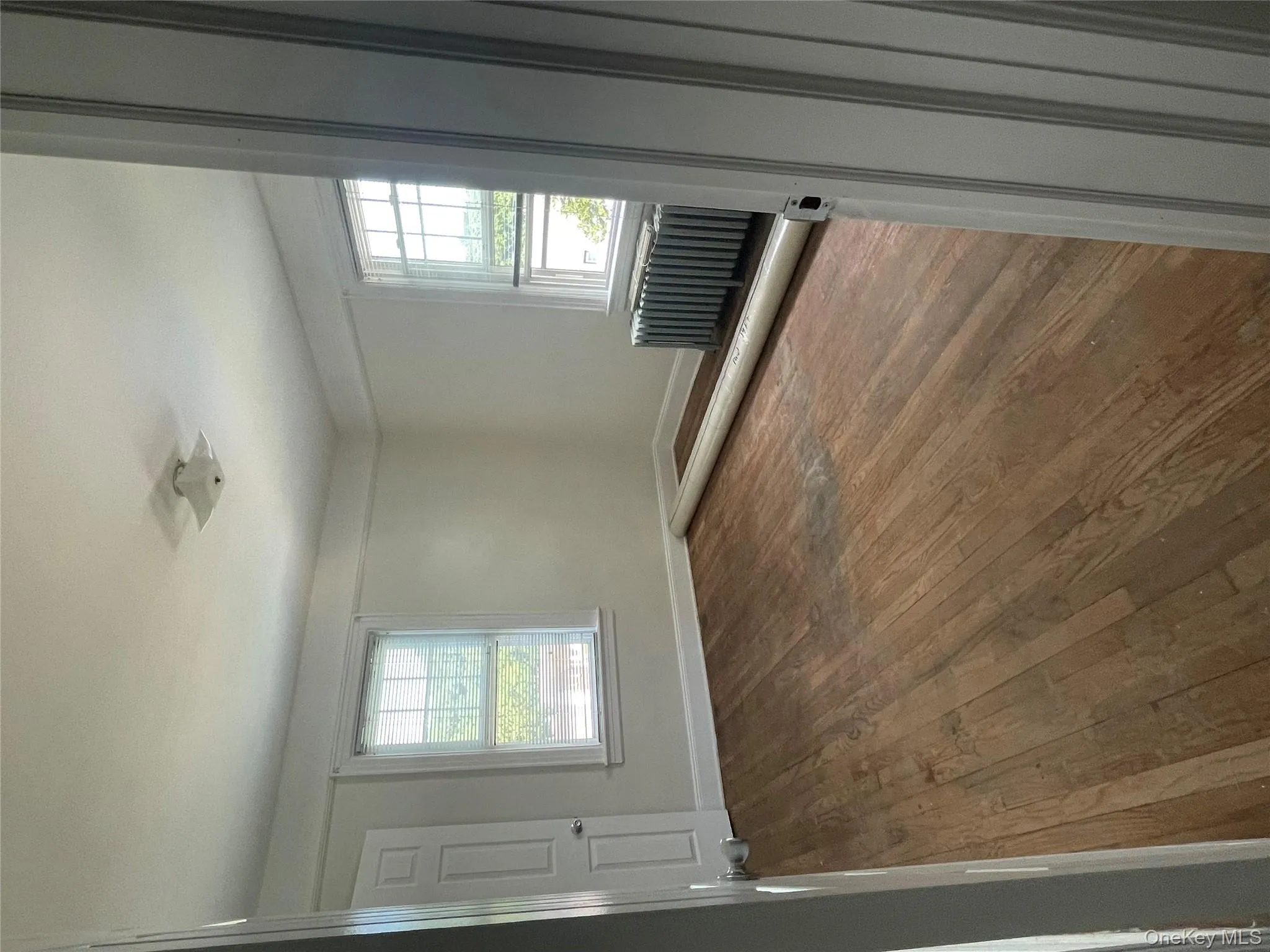 Spare room featuring healthy amount of natural light, dark wood-style floors, and radiator Spare room featuring healthy amount of natural light, dark wood-style floors, and radiator