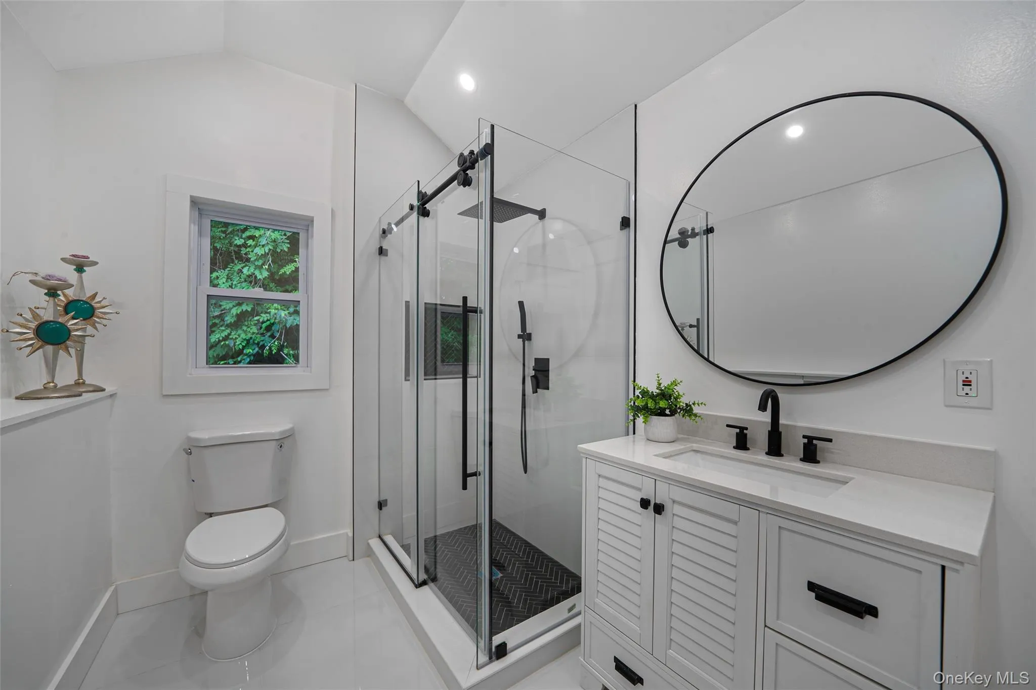 Bathroom with vanity, a stall shower, vaulted ceiling, and tile patterned flooring Bathroom with vanity, a stall shower, vaulted ceiling, and tile patterned flooring