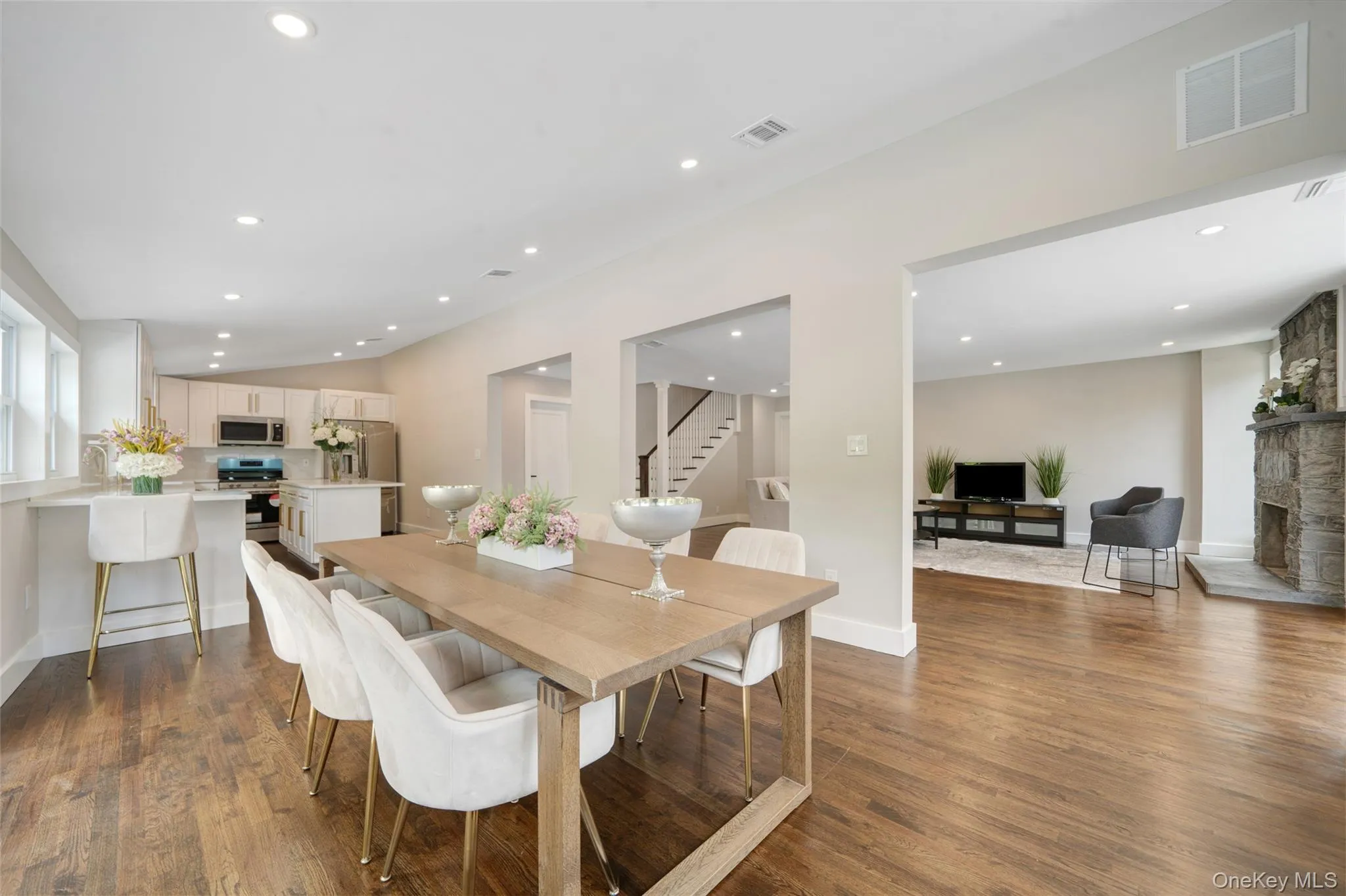 Dining space featuring stairs, dark wood-type flooring, recessed lighting, and a stone fireplace Dining space featuring stairs, dark wood-type flooring, recessed lighting, and a stone fireplace