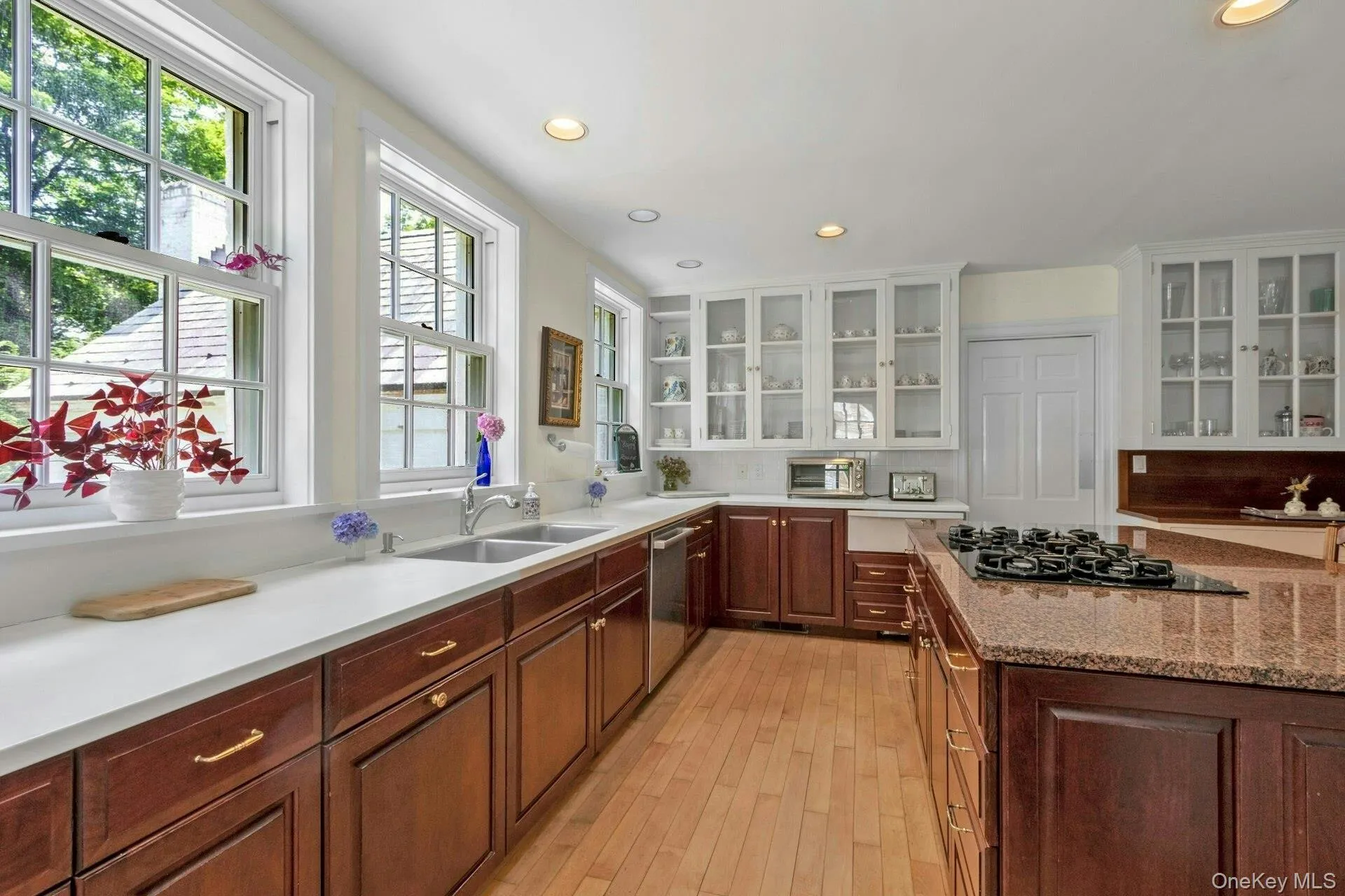 Kitchen featuring recessed lighting, light wood finished floors, white cabinets, black gas cooktop, and glass insert cabinets Kitchen featuring recessed lighting, light wood finished floors, white cabinets, black gas cooktop, and glass insert cabinets